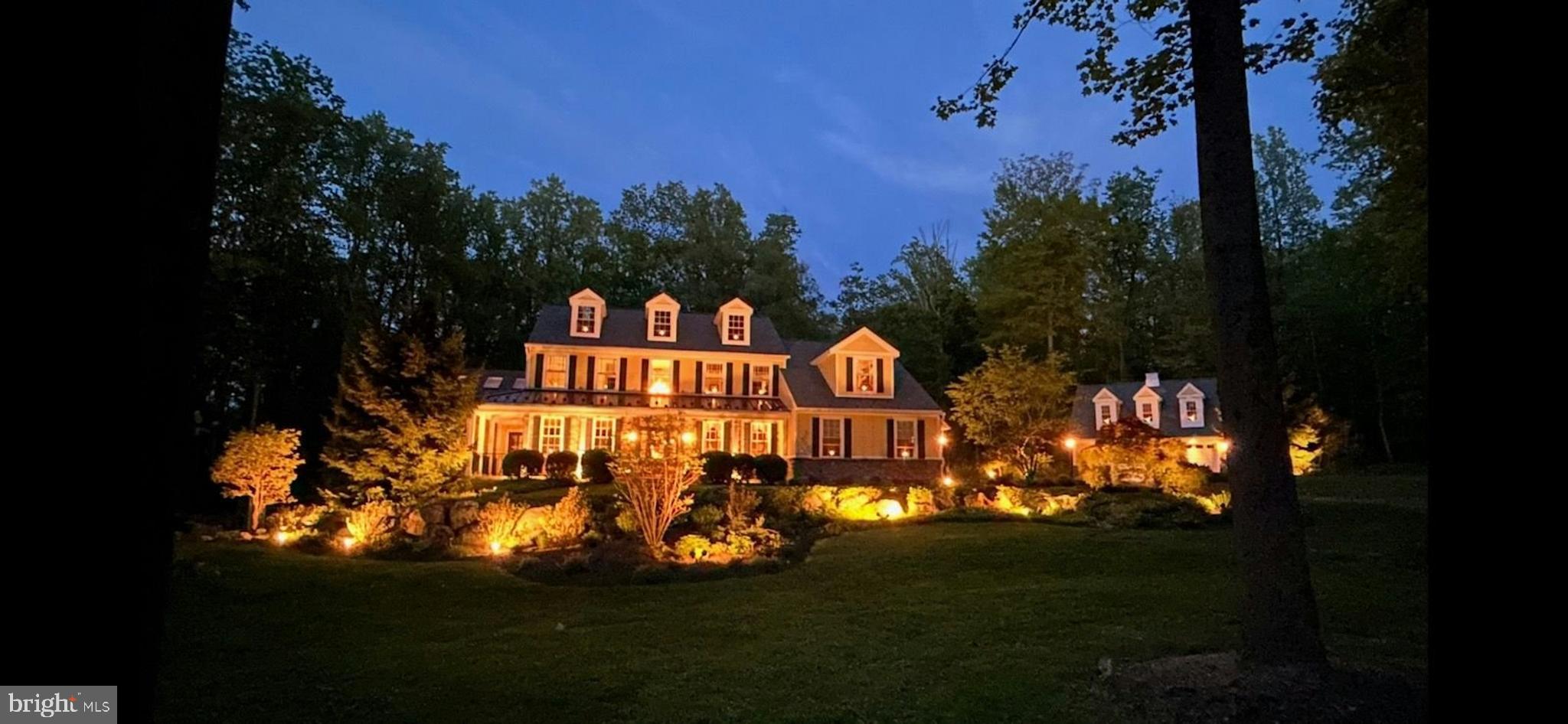 Set back from a quiet country road, Ridgewood is nestled on nearly 6 wooded acres in a corner of Bucks County that is easily accessible to Coopersburg and Bethlehem. Tastefully renovated and upgraded with the flair of an artistic eye, the home has a surplus of sun-splashed rooms and luxury finishes that include custom high-end moldings. Creatively designed and unforgettable, the family room addition is highlighted by a soaring circa 1852 barnboard ceiling with skylights, floor-to-ceiling stone fireplace and walls of windows. This room is just one of the many treasures inside this elegant home. A renovated kitchen with handmade copper sink, granite counter and handmade Italian backsplash showcases Sub-Zero appliances and beverage center and a Wolf 6-burner gas range with pot filler. The open floor plan flows from the kitchen, through the breakfast room and into the expansive great room with a 2nd floor-to-ceiling gas fireplace.
The sophisticated primary suite offers tray ceiling, lofted sitting area and renovated luxury bath with Italian onyx tile floor, river rock shower and enviable walk-in closet. This home constantly delights you with the unexpected. The walk-out lower level presents options for versatile family dynamics and lifestyles. Here a richly outfitted kitchen with quartz countertops and stainless appliances accommodates the den with fireplace, game room, bonus room and upscale full bath.
The updated maintenance-free exterior includes Hardie plank siding, Azek trim, handmade cedar shutters, custom mahogany wood doors, leaf guard system, large multi-level Trex deck, wrap around front porch and bluestone patio with oversized stone firepit. Park-like professional landscaping by Plantique and Jerry Fritz Design is highlighted by extensive landscape lighting. Garaging is accommodated by the 3-car attached garage with epoxy flooring and additional 2-car detached garage with finished 2nd level office or flex space and custom moldings.