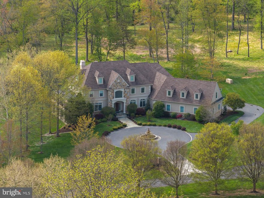 Experience exceptional luxury on 4+ acres in one of Solebury Township’s most coveted enclaves. Ideally positioned on a cul-de-sac, this custom-built Bucks County estate offers a rare combination of acreage, privacy, and architectural presence—introduced by a stately circular drive and fountain that set the tone for what lies beyond.

Step into the marble foyer with a gorgeous curved staircase and premium trim work.  Designed with both everyday living and elevated entertaining in mind, the chef’s kitchen features radiant heated floors, professional-grade stainless appliances, expansive granite surfaces, and an oversized center island with secondary dishwasher and refrigerated drawers. The dramatic 20+ foot coffered family room is anchored by a stone wood-burning fireplace and framed by walls of windows overlooking a serene lawn and beautiful treed meadow beyond. Formal living room with gas fireplace, formal dining room, a butler’s pantry complete with wet bar, and a private office featuring custom built-ins and access to a wraparound covered porch complete the main level.

Upstairs, the primary suite offers a true sense of retreat, with a spacious sitting area, dual walk-in closets, tray ceilings, and a separate flex space ideal for a custom walk-in closet, gym, or perhaps a large second floor laundry room. The spa-inspired bath features a steam shower, jetted soaking tub, dual vanities, and radiant heated floors. Three additional ensuite bedrooms and a full third-floor princess suite provide comfort and privacy for family and guests.

The finished lower level is thoughtfully designed for entertainment, featuring a pub-style bar, gaming area, a dedicated home theater with projection and surround sound, along with another bonus room, a full bath, and a large workshop. And its wall of windows and connection to the backyard do not disappoint.

Outdoors, the expansive grounds offer endless potential, with ample space for a future pool and outdoor kitchen, complemented by patios and a wraparound covered porch. Additional amenities include a generator, an alarm system, and a heated 4+ car garage with premium SwissTrax flooring, many cabinets and shelves, and stairs leading directly to the basement.

Located within the award-winning New Hope–Solebury School District and just minutes from the vibrant rivertowns of New Hope and Lambertville—with convenient access to New York, New Jersey, and Philadelphia—this property represents a rare opportunity to own a private estate of this scale and caliber in the heart of Bucks County.