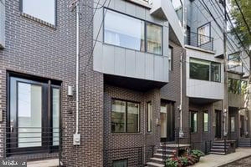 819 N  Orkney  Street is part of the exclusive SEVENTEEN townhome enclave, a gated boutique grouping of residences  showcasing modern luxury and elevated design with striking graphite brick and aluminum composite façades which set a bold tone and intriguing curb appeal. This stunning dwelling offers approximately 3,200 square feet of thoughtfully designed living space across five well planned levels, blending industrial-inspired elegance with contemporary comfort. From the moment you enter the private motor court through large format custom designed iron gates and pull right into your private 2 oversized garage, the attention to detail and upscale finishes are evident.  These  architectural gems located in the heart of Northern Liberties featuring  three spacious bedrooms, three and a half  luxurious bathrooms are finished in Carrera marble,  Porcelanosa tile and feature Grohe and Toto fixtures. The primary bedroom has an abundance of thoughtfully designed and handcrafted custom built storage and closet spaces for all of your clothes and accessories, one also houses a television center which can be closed and hidden when not in use, in addition a large custom walk in closet and a beautifully designed dressing station with further walk in closet and storage space. The fully finished basement ideally functions as a comfortable year round media room with an additional abutting finished room lined with  multiple storage closets is ideal for in home fitness, a remote office, game room or even as an optional fourth bedroom. The home features soaring 9’ to 14’ ceilings, stunning Brazilian Tigerwood  floors, Pella Architect Series windows, custom steel stair railings, and a built-in Sonos sound system with ceiling speakers in the kitchen, family room, basement, and primary suite. The Poggenpohl kitchen with extra upper cabinets and built in pantry is perfectly equipped  with Thermador Professional appliances, sleek soft-close cabinetry, and quartz countertops, making it ideal for both everyday living and entertaining.  Off of the kitchen and dining area is a large Trex balcony that spans the width of the home is perfect for outdoor grilling,  morning coffee and some urban gardening. Smart home features Schlage door locks, Nest thermostats, and fire and C/O detectors throughout, along with 4" recessed lighting in every room in the home. High speed internet is powered not only through WiFi but also  CAT-5 wiring  across all living spaces in the home ensuring seamless connectivity. The basement includes a media and security closet wired for multiple devices. The garage is fully outfitted with two ceiling-mounted 4’x8’ storage racks. Dual high-efficiency Lennox HVAC systems provide year-round comfort, and the home is efficiently run by NEST smart thermostat system and Airphone video intercom security. Atop the home is a large pilot house leading to a private green roof and Trex deck area  offering  sweeping city views, incredible daily sunsets and is an ideal space for outdoor entertaining or relaxation throughout the day and night. Located in one of Philadelphia’s most dynamic neighborhoods, this home is just steps away from notable favorites like Cafe La Maude, Honey’s Sit ’n Eat, One Shot Coffe and Liberty Lands Park, with nightlife and entertainment nearby at Yards and Urban Village Brewing, and North Bowl. Other new convinces are a Sprouts Market and Amazon Fresh Grocery within walking distance. This is truly  a rare opportunity to own a completely  turnkey luxury home in one of the city's most sought-after communities.