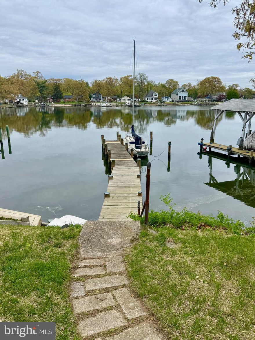 Charming 3 bedroom Bodkin Creek deep waterfront with stellar panoramic water-views, mature shade trees and steady bay breezes. Located in the spectacular, peninsula community of Poplar Ridge, is this charming and spacious 4 level home with an attached one-car garage, ready for your vision. The home's bluff-top elevation shaded by majestic oaks and perched approximately 15 feet above the shoreline provides an absolutely gorgeous waterfront setting with panoramic views of Back Creek of the Bodkin. Enter into the large living room with wood-burning fireplace. The living room and adjacent dining room with built-in cabinetry and hardwood floors both have waterfront views. The upper level has 3 bedrooms also with hardwood floors, 1 full bath. The slightly lower ground floor level has a finished family room that could serve as an office, with a street-side entrance door and a half bath and adjacent laundry room that could easily be converted to a 2nd full bath.  Approximately 54 feet of bulkheaded sand-bottom shoreline and a private pier with typical 7'+ depth and mooring pilings framing a deep draft big boat slip. This lot and home are primely positioned to take advantage of one of the best boating destinations the east coast has to offer! Located within minutes of the mouth of the Bodkin and the Chesapeake Bay. In just 30-45 minutes, boat to Annapolis, Rock Hall, the Magothy River, Kent Island and Baltimore! Or stay close to home and anchor to enjoy the sunrises and sunsets in the grand basin of the Bodkin, where Main Creek and Back Creek converge. Don't miss this tremendous opportunity to live the Maryland waterfront lifestyle. As-is sale.