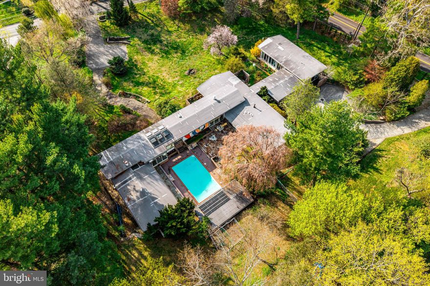 This is a house with a LOT of wow factor! If you're a fan of mid-century modern design, prepare to be charmed by this authentic gem. Its soaring ceilings, sun-drenched rooms, and a seamless flow between indoor and outdoor spaces create an inviting, one-of-a-kind home.
Thoughtfully designed in 1956 by a premier Philadelphia architectural firm, Carroll, Grisdale & Van Alen, on nearly two acres in Penn Valley, it presents a rare opportunity to own a piece of architectural history. The house wraps around a beautiful flagstone courtyard and pool, with a pool house to complete the 4th wall. Go up the winding flagstone path to enter through dramatic double doors into a striking foyer, complete with a water feature, statement chandelier, and a Hollywood-style powder room. To the right, the private primary suite awaits, complete with a cozy gas fireplace, dual en-suite bathrooms, and custom walk-in closets. Adjacent to this suite is a spacious living area, currently utilized as a gym but previously showcased as an art gallery. This wing also provides access to an expansive lower level, offering abundant storage and a Swedish sauna. On the opposite side of the foyer and pool, the main living areas unfold, featuring a generous living and dining space, a family room adorned with a fireplace and built-in bookcases, a kitchen, powder room, laundry room, and three bedrooms, each with its own en-suite bath,  Two bedrooms have their own private courtyard, the third bedroom currently serves as a convenient pool room for post-swim relaxation, though the pool house itself also offers a full bath. The kitchen stays true to its modernist roots, enhanced by three floor-to-ceiling pantries that provide ample storage. Architectural details like soaring ceilings with wooden beams, abundant windows, a wall fountain by the pool, and an abstract mural adorning the pool wall further highlight the home's mid-century modern charm. Finally, off the main house there is a separate section with its own entrance features three flexible rooms including a full Jack and Jill bath and a powder room, making this wing ideal for offices, guest suites, or in-law living. Recent upgrades encompass a new HVAC system, an active radon system, new pool mechanicals and paving stones, retaining walls and carpeting.
This sprawling ranch, with its five to six bedrooms and six full baths, is perfectly suited for entertaining, remote work or multigenerational living. Each bedroom offers peaceful garden or courtyard views, making every space feel like a private retreat. Additional features include a two-car attached garage and a detached storage shed. Bonus: it’s in the award-winning Lower Merion School District with easy access to Center City.