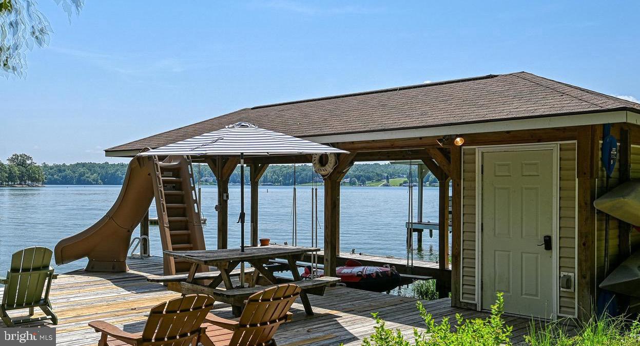 RARE opportunity and price improvement! Completely furnished luxury waterfront log home, with incredible water views, MANY recent upgrades, and all the bells and whistles you could ask for. You will not find more "bang-for-buck" anywhere on Lake Anna. This warm and cozy escape perched on the public side of Lake Anna will recharge your batteries, create life-long memories, and deliver the lake-front experience you've been searching for. Down at the water's edge, your private waterfront area in a protected cove includes nearly 100 feet of beautiful Lake Anna shoreline, as well as your very own private boathouse, with newly-installed waterslide - including water pump that activates water down the slide, a boat slip with electric lift, kayaks to explore the lake, a lockable storage room full of water toys, and a seating area to relax on summer afternoons. Back at the house, you'll experience some of the best water views Lake Anna has to offer! The house itself has recently enjoyed numerous upgrades, including a beautiful new enclosed screened-in porch with relaxing furniture, facing the water. The main level features beautiful exposed beams overhead, tongue-in-grove ceiling boards, and hardwood floors. The recently upgraded kitchen offers granite countertops, stainless appliances, pantry, backsplash, and peninsula with cooktop, all of which seamlessly ties into the dining area and spacious living room, showcasing a large brick fireplace, chunky hearth, and warm shiplap walls. The main level also includes one bedroom with bunkbeds, a recently added laundry area, and full bathroom. Your guests can spread out in two additional, very spacious bedrooms upstairs, one of which includes its own private balcony overlooking the lake. Full bathroom with shower upstairs, as well. Unwind in your own private hot tub conveniently mounted down into the back deck facing the water, alongside the BBQ grill, deck, and sitting area. Additionally, the owners recently added "The Game Room" (an EXTRA 200+ conditioned square feet), which is a cozy, temperature controlled shed with air hockey, foosball, darts, corn hole, and other fun games to enjoy. This property also comes with a detached garage, covered car port, fire pit, swing, and tetherball game. This property is an active short term rental; rental history available on request. Completely turn-key opportunity: furniture, furnishings, decor, and water toys all convey with your purchase. Whether you are searching for the perfect weekend getaway, or a STR property, this fact cannot be overstated: you will not find more "bang-for-buck" anywhere on Lake Anna. This property was briefly off-market due to owner refinancing.
