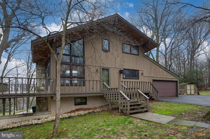 Nice Contemporary home located on a wooded lot in East Hempfield township's Pennwood neighborhood. Feels like stepping into the mountains. Enjoy the magnificent living room with a large stone fireplace with heatilator. Surrounded by large windows. It adjoins the kitchen with loads of counter space. There is a first-floor bedroom and full bath. The second floor has two bedrooms, one which has a cathedral ceiling and a full bath.  There is daylight lower level that has a large living / den area with fireplace and a kitchenette plus 2 bedrooms and an additional full bath.
There is a 2-car garage and nice wrap around decks. Come see this great home. Buyer agent to confirm Sq Footage tax records may not be accurate.
