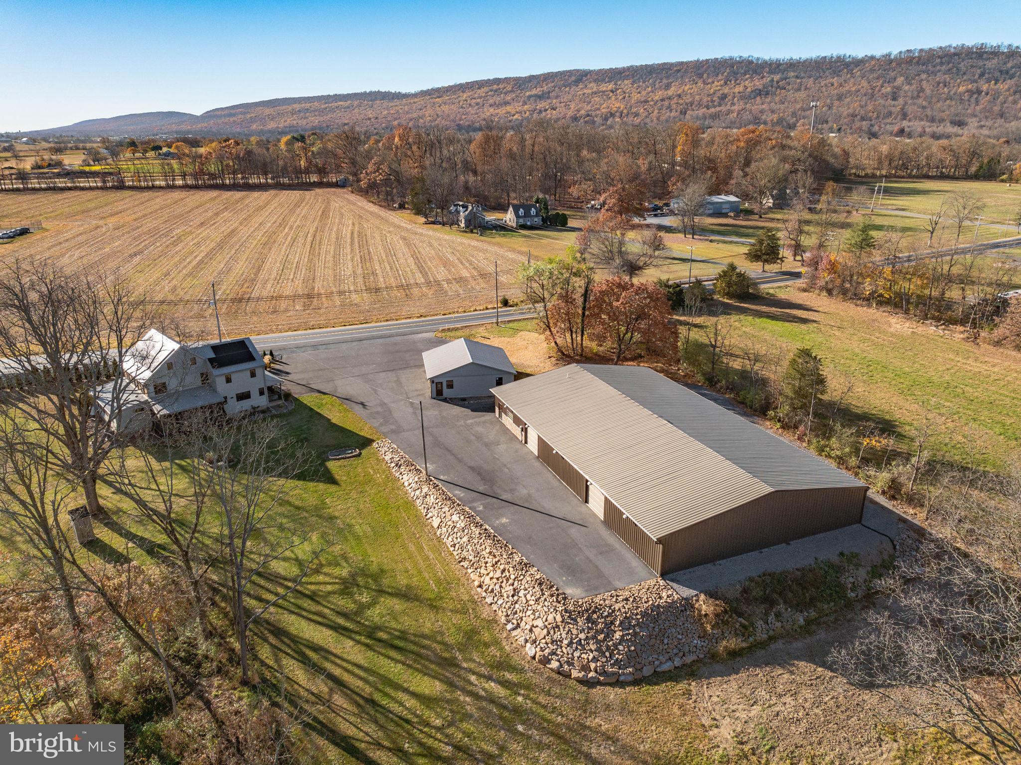 This rare and beautifully renovated 3-story American Chestnut log home, dating back to the early 1800s, offers a unique blend of historic charm and modern amenities with the endless possibilities that comes with the dream car enthusiast's commercial garage. COMPLETELY renovated in 2017, the home has been updated inside and out, preserving its original character while incorporating all the conveniences of contemporary living. Situated on a sprawling property that borders state game lands and a rail trail, the home is perfect for those seeking a peaceful retreat with easy access to outdoor recreation, including excellent hunting opportunities.
The interior of the home boasts exposed original beams with new chinking and new drywall, while the custom-made solid wood 42" Alder front door makes a stunning first impression. Inside, you’ll find a fully updated kitchen with Kraftmaid cabinets, quartz countertops, a center island, and high-end Samsung stainless steel appliances, as well as a custom-built wood 2-person desk and solid wood bookcases in the loft. The spacious living room with is enhanced by a new propane fireplace, adding warmth and comfort to the space. The home features a new on-demand propane water heating system, a new electrical panel and wiring, new plumbing with PEX tubing, new flooring, all-new windows, and solid wood interior doors throughout. The bathrooms have been completely updated with modern fixtures, including a luxurious new double tile shower and whirlpool double tub. The master suite features a walk-in closet, and there is ample closet space throughout the home, including huge closets on the first and second floors. For year-round enjoyment, the enclosed 3-season porch includes custom folding tinted blinds, providing a perfect spot to relax.
The home has been upgraded with modern systems, including a new central air and heating system, a new metal roof, and all-new siding for long-lasting durability. The two-year-old blacktop driveway leads to a newly remodeled 36' x 36' 3-car garage with commercial-grade electric wiring, new doors, and Genie openers. Adjacent to the home is a 120' x 70' commercial steel building with underground utilities, radiant floor heating, office space, utility rooms, a work area, a showroom, and a bathroom. Currently zoned for use as a state and township-approved classic car dealership, the building can be maintained for its current purpose or repurposed to fit the buyer's needs. The property is supplied by two working 1800s hand-dug wells, both updated with modern plumbing—one servicing the house and the other the commercial garage. The entire property offers incredible potential for residential or commercial use, with the flexibility to continue the current business operation or transform the space into something entirely new.
Conveniently located near I-81 and I-78, this home provides both privacy and accessibility, offering a rare opportunity to own a historic home with all the amenities and infrastructure needed for modern living. Whether you're looking for a unique residence or a versatile business space, this one-of-a-kind property is a must-see.