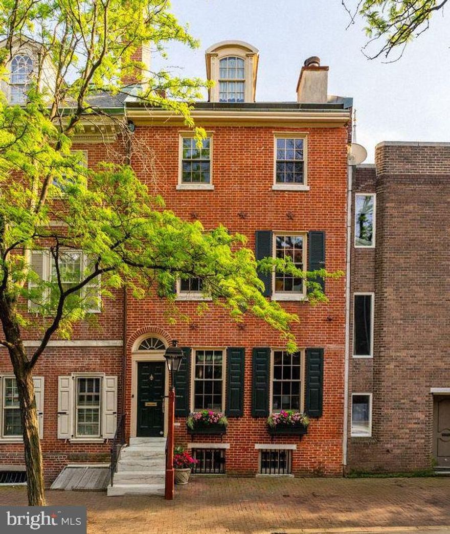 Exceptional c.1830 Federal-style home on the Historic Registry, located on the iconic 300 block of Delancey Street in Society Hill. This 20' wide property blends historic charm with modern updates and sits on a picturesque, cobblestone street near the Physick House and the beloved Three Bears Park. The elegant foyer leads to a bright, open first floor with a spacious living room featuring built-ins and a wood-burning fireplace, a formal dining room with architectural columns, and a sunlit eat-in kitchen overlooking a brick patio with café lighting. A tucked-away powder room and designer fixtures complete the main level. The second floor features a spacious front-facing primary bedroom with a gas fireplace, as well as a separate office and a full bath with double vanity and a clever dual-access design. The third floor offers two additional bedrooms, a full bath, and access to a south-facing deck with ample sunlight and a retractable awning. The top-floor dormered suite includes its own full bath and offers sweeping views of St. Peter’s steeple and the Ben Franklin Bridge. The finished basement boasts high ceilings, exposed brick, built-ins, and separate utility/laundry/storage space. Recent upgrades include newly refinished hardwood floors, custom millwork, upgraded lighting, 3-zone HVAC, new heater and water heater, and a drip irrigation system. A rare opportunity to live on this coveted block in Society Hill, just steps from world-famous restaurants, historic sites, parks, markets, and the new Delaware River Trail.