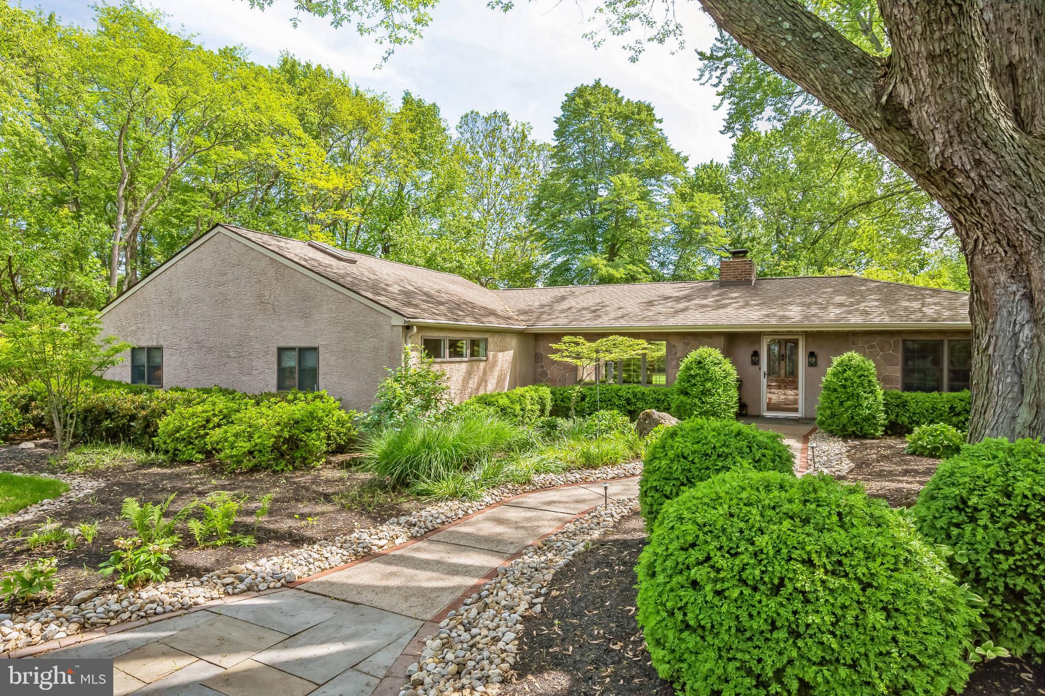 Set on 1.18 acres in the heart of charming Bucks County, this welcoming one-story rancher offers a peaceful retreat with timeless appeal. Located in the highly regarded Pennsbury School District, the home blends classic character with a efficient, flowing layout and serene surroundings. The expansive great room is the heart of the home, featuring rustic wood beams, 7-inch natural wood baseboards, a brick-front wood-burning fireplace, built-in shelving, and a full wall of windows that bathe the space in natural light. The dining area is tucked within this open space, making it perfect for entertaining or simply enjoying everyday meals by the fire. The kitchen is both functional and inviting, with a spacious center island topped in 2-inch butcher block, wood-beamed ceiling, recessed lighting, modern tile backsplash, stainless steel appliances, and a sleek hooded range. There is a walk-in pantry for additional storage and functionality. A separate den, office, or 4th bedroom with a custom stained-glass window offers a quiet spot to work or relax. The spacious primary bedroom features hardwood floors, crown molding, a ceiling fan, and recessed lighting, along with a spacious spa-styled en-suite bath with a doorless walk-in shower adorned with designer tile. Two additional bedrooms, also with wood floors, share a full hall bath complete with a jetted tub, raised ceiling, skylight, and soothing wall fountain to provide maximum relaxation. Step outside to the covered back porch and enjoy the peaceful setting—ideal for morning coffee or summer evenings. A large backyard shed with a work area adds extra versatility to the outdoor space. Lovingly maintained by its current owners, the home has seen thoughtful updates, including siding, stucco, kitchen renovation, both bathroom renovations, new well equipment, a geothermal water heater and heating and cooling system, and the addition of the covered patio. Full of Bucks County charm and move-in ready, this home is a true gem. Minutes to the small country towns of Yardley, Newtown, and Washington Crossing, enjoy the charm that these towns offer. Near 295/95 for access to all other major commuting arteries. Only 20 minutes to trains to NYC.
