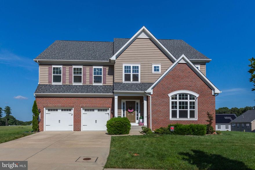 This exceptional six-bedroom, five-bath brick-front colonial, built in 2017, is perfectly perched on the highest ground and largest lot in the desirable Centennial Lake Overlook community, offering unmatched privacy, views, and space. Freshly painted and enhanced with stylish new light fixtures, this meticulously maintained home is truly move-in ready. A grand two-story foyer, gleaming hardwood floors, and abundant natural light welcome you inside. The main level features a flexible bedroom ideal for a home office or guest suite, conveniently located next to a full bath. The chef’s kitchen impresses with a large island, granite countertops, tiled backsplash, stainless steel appliances, and a butler’s pantry leading to the formal dining room. The kitchen opens seamlessly to a dramatic family room with soaring ceilings and a stunning two-story stone fireplace. Step outside to a custom deck—ideal for entertaining and enjoying the expansive backyard. Upstairs, four generously sized bedrooms each offer direct access to bathrooms, including a luxurious primary suite with tray ceilings, a spa-like en-suite bath, and a massive walk-in closet. The fully finished walk-out basement provides even more living space with a sixth bedroom, full bath, and a spacious recreation area perfect for guests or extended family. Located in a top-rated school district with direct access to Centennial Park and close to shopping, dining, and Route 29, this home offers the perfect blend of luxury, location, and lifestyle.