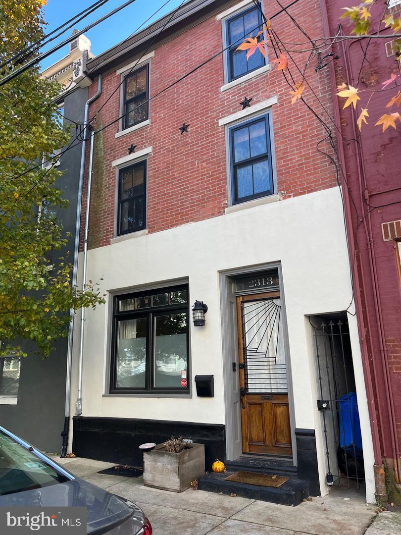 Thoughtfully Rebuilt Row home with Custom Craftsmanship & Outdoor Space. Owner prefers the house be rented fully furnished (furniture as is in the pictures) but may be negotiable to rent without as well.
This stunning 3-bedroom, 2-bathroom home offers a modern take on the classic Philadelphia row home, blending custom design with vintage charm. Meticulously rebuilt from the studs by a local builder in 2015, every detail has been carefully curated to create a home that feels both refined and inviting.
Step through the oversized vintage wood-and-glass front door into a bright, serene living space with natural light pouring in from windows on three sides. The main floor features an open layout with original hardwood floors, a craftsman-built steel staircase, a striking concrete kitchen countertop, and reclaimed wood cabinetry—just a few of the bespoke elements that set this home apart.
Off the kitchen, you'll find the first of three private outdoor spaces: a large rear patio ideal for grilling, lounging, or entertaining. There's also gated alley access for discreet storage of bikes, trash, recycling, or gardening tools.
Upstairs, two well-sized bedrooms offer generous closets, one with access to a private deck, and a full bathroom with a sliding barn door, a tub, and a convenient stacked washer/dryer.
The entire third floor is a dedicated primary suite, featuring exposed brick, restored original pine floors, a spa-like bath with penny tile, frameless glass shower, rainfall showerhead, and another private deck—your own peaceful retreat.
Additional features include central air, LED recessed lighting, an installed security system, Nest thermostat, and a high-efficiency furnace. The full basement offers excellent storage and houses the home's updated mechanicals. The home is insulated to modern standards and enjoys gorgeous morning light with southeast rear exposure.
Located on a quiet, tree-lined block just three blocks from the El, you're moments from Loco Pez, Franny Lou’s Porch, Philly Brewing Co., and the best of Frankford Ave and Front Street’s cafes, boutiques, and nightlife.
A true gem with character, craftsmanship, and convenience—this home is unlike anything else on the market.