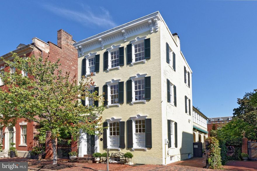 Nestled in the heart of Old Town, this magnificent Victorian residence exudes elegance and offers a unique opportunity to own a piece of history.  Built in 1870, this freestanding brick home sits on a beautiful tree-lined block and its picturesque façade with decorative window pediments and cornice add to the inviting curb appeal.  High ceilings, tall windows, original heart pine floors, 2 wood burning fireplaces, handsome millwork, and other fine details showcase the perfect blend of old-world craftsmanship with modern conveniences.

The multi-story interior is gracious and enchanting, introduced by a welcoming double door vestibule with marble flooring, spacious front hall with an original staircase and shadow rail, high ceilings, and an antique bell chandelier.  Gorgeous original 9’ double doors with hardware open to the generously proportioned living room with 10’5” ceilings where entertaining is effortless.  Natural light streams through tall windows on two sides with original folding shutters and a wood burning fireplace with an ornate mantle makes an elegant statement.  A wonderful formal dining room is a lovely setting for gatherings.  Delight the chef in the sunny kitchen equipped with new stainless appliances, a period fireplace, abundant cabinetry, decorative corner china cabinet, and access to the covered veranda.  Enjoy morning coffee or a casual meal in the triple windowed eat-in area overlooking the expansive brick patio.  Completing the main level is a convenient powder room to accommodate your guests.

The second level presents a generous family room, ideal for relaxing, with many windows and built-in bookshelves.  A delightful guest suite provides a comfortable setting for family or guests with a door to access to the fabulous sunroom. The light-filled primary suite is a private respite featuring a dressing room with large closets, custom built-ins, access to the bright sunroom, and an updated bath with seamless glass shower and marble vanity.  The third level offers two additional bedrooms, full bath, and a cedar closet. Other special features include a large lower level with built-in shelving, additional storage, and a laundry area with sink.

Savor the outdoors on the deep covered porch with intricate wrought iron embellishments or on the expansive patio garden retreat surrounded by mature trees and specimen plantings.  Outdoor enthusiasts will enjoy reading or relaxing in the gazebo or working in the potting shed.  One off-street parking space beyond the iron gate completes this important property..  This historic gem enjoys a prime location on one of Old Town’ sought-after streets, minutes to shops, restaurants, parks, and the Potomac River.  Now is the time to embrace the chance to create new memories in this remarkable residence.