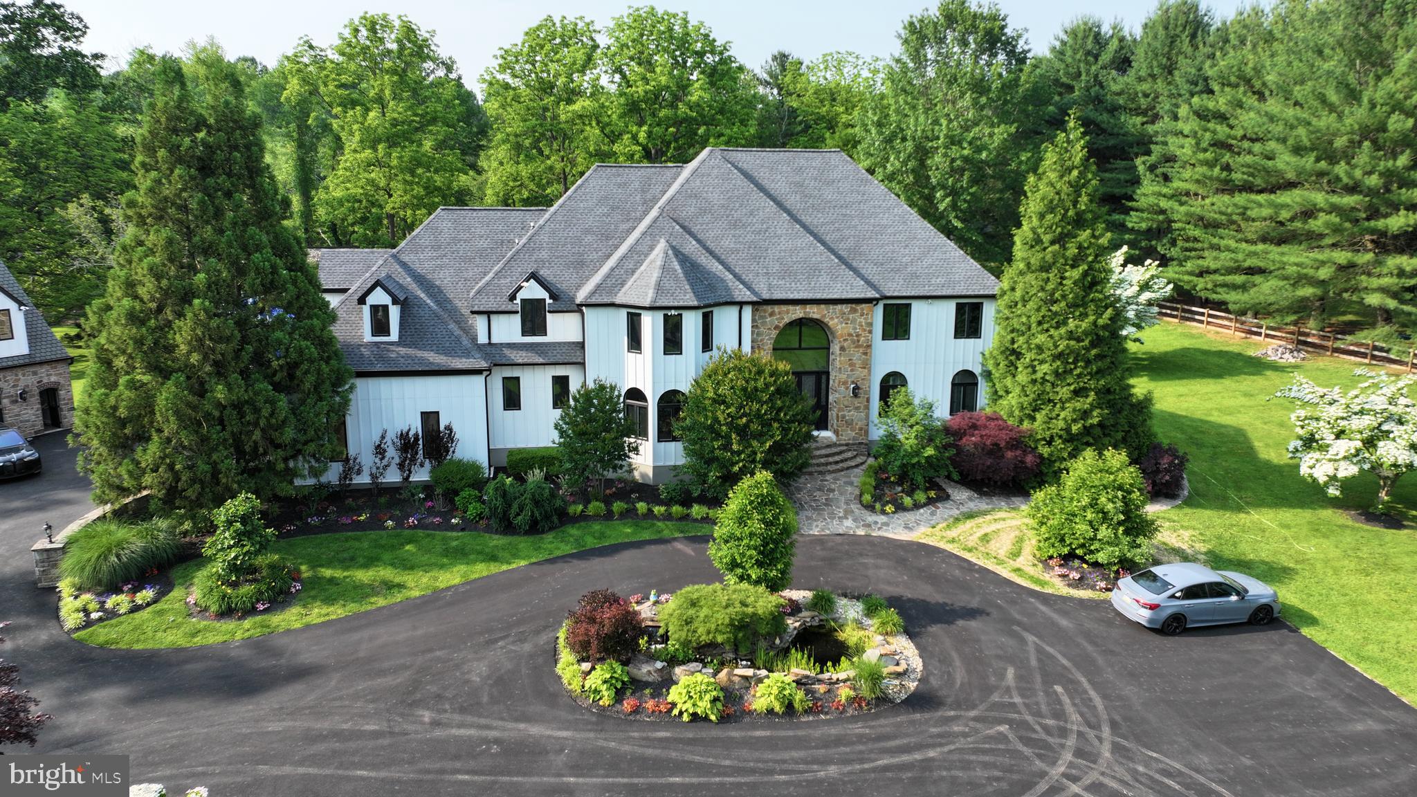 Welcome to this exceptional estate in the heart of the Brandywine Valley, offering over 6,800 square feet of luxurious living space on more than 3 acres of beautifully landscaped grounds. This stunning 5-bedroom, 4 full-bathroom, and 2 half-bath home has undergone numerous recent upgrades, including new hardie board siding, brand new windows and doors, entirely renovated kitchen, new hardwood floors throughout, fully remodeled bathrooms - and so much more! All of these updates contribute to its modern appeal and timeless charm. As you arrive, you’ll notice the bold landscaping, newly paved circular driveway, and unmatched privacy upon entering your gated retreat. A detached 6 car garage with a full attic, basement, and half-bath completes this exceptional property—a true dream for car enthusiasts.
Upon entering the main house, you’re greeted by a dramatic two-story marble foyer with a sweeping curved staircase. The home is designed with gorgeous 4-inch hickory hardwood floors throughout the first level, adding warmth and sophistication. To the left, the formal dining room with custom wood trim is ideal for elegant entertaining. The newly renovated chef’s kitchen is a standout feature, with white cabinetry, a custom 17-foot island with seating, quartz countertops with an inlay, a cooktop, double ovens, built-in refrigerator and freezer, and a convenient butler’s pantry. The kitchen offers stunning views through the accordion window, and an accordion door opens directly to the covered porch, seamlessly blending indoor and outdoor living. Off the kitchen you’ll find a mudroom and half bath for easy guest access. The sunken great room, with intricate millwork and a marble gas fireplace, provides ample seating space and offers more beautiful views. You will also find a master suite which includes a large ensuite bathroom including two single vanities, two toilet rooms, a beautifully renovated stand up shower and two walk in closets. This room also offers its own private entry to the deck. Upstairs, the hardwood floors continue to four additional spacious bedrooms, a laundry room, and a private movie theater. The luxurious owner’s suite features vaulted ceilings, wall-to-wall carpeting, a floor-to-ceiling gas fireplace with marble surround, a private balcony, dual walk-in California closets, and an impressive en-suite bathroom with dual vanities, a large stall shower with multiple showerheads, and a soaking tub. Two bedrooms share a modern Jack-and-Jill bathroom with a stall shower and dual-sink vanity. Another bedroom offers its own en-suite bathroom with a beautifully renovated stand up shower and dual sink vanity. The conveniently located laundry room adds practicality to this level. The private theater room, complete with projector screen, custom cabinetry, mini fridge, and sink, offers the perfect setting for entertainment, or can be turned into an additional bedroom. There is a large bonus room off the kitchen that would make a great gym, game room or conversation room - utilize it as you need. This space offers a wonderful flow towards the outside of the home. The unfinished basement provides a blank canvas for future use with its 8 foot ceilings and walk-out access to the exterior, allowing for endless possibilities to expand and customize.The backyard is an entertainer’s dream, featuring a brand-new oversized deck, both covered and open. The deck is perfect year round offering a fireplace, television, skylights and plenty of space for friends and family to gather. For those hot summer days you can sit at the newly renovated in-ground gunite pool with a beautiful paver patio, updated pool equipment and over the top waterslide. The private pool house includes a full eat-in kitchen, laundry area and two bedrooms, each with its own en-suite bathroom, offering guests a luxurious and private retreat. This makes for a perfect in-law suite! This estate perfectly blends luxury, privacy, and modern amenities.