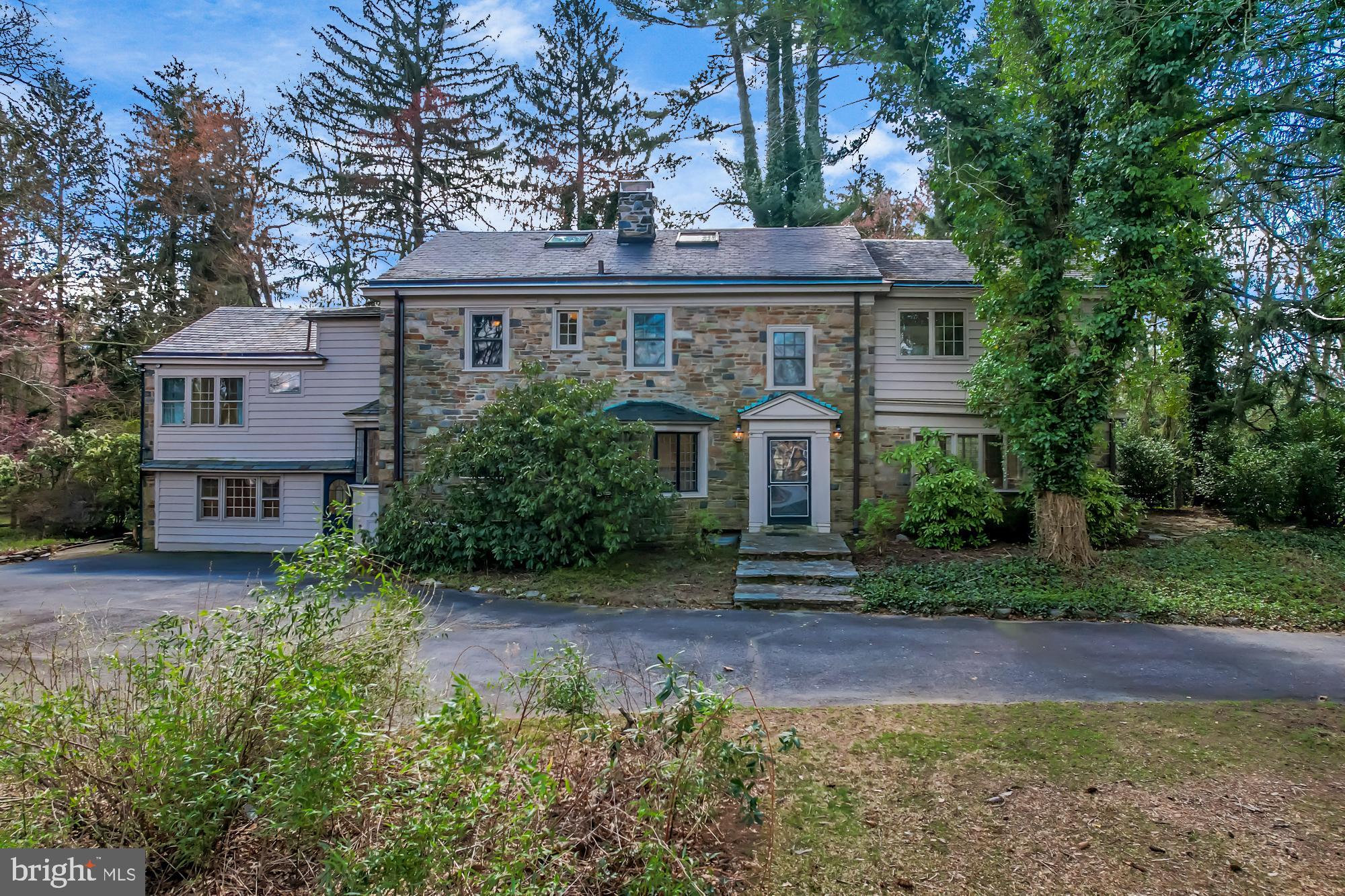 Nestled on a quiet cul-de-sac street in Westtown Township, this spectacular 1.4-acre property is a rare find in the area, offering the chance to create a truly one-of-a-kind, magnificent estate. It features a grand stone home, built in 1933, an in-ground pool, and a large, detached garage. Old world charm abounds here, from the hand-crafted inlaid tile in the foyer to the original hardwood floors to the many built-ins and crystal doorknobs. Enter the front door and you’ll find a sitting room with a gas fireplace tucked to the side of the foyer—the perfect place for a library, music room or home office. The foyer opens to a stunning living room with random-width hardwood floors, a fireplace, and a wall of windows and French doors offering sweeping views of this beautiful property. This living room spans nearly the entire back of the house, and the French doors lead to a raised stone patio so expansive that you could host a wedding! A conservatory, with a coffered ceiling, sits to the side, also with windows all around and two French doors leading to both the patio and an adjacent courtyard. To the other side of the living room is the kitchen, updated with a Viking range, SubZero refrigerator, and farmhouse sink, and made warm with rustic, salvaged beams, and cherry cabinetry. There is also a powder room nearby. The unique architectural design and details of this home continue upstairs, where you’ll find four bedrooms and three full baths set off an open hallway that’s big enough to be a sitting room. These include a main bedroom suite with a soaring cathedral ceiling, a full bath offering a large shower plus a standing tub, and a walk-in closet. This home also has a separate suite with two rooms, a full bath, its own entrance and endless possibilities as a home office, studio, additional sleeping rooms, or au pair/in-law quarters. Back stairs from the kitchen connect to this space as well as to a finished attic with skylights. Below the suite, and off the side door, is the spacious laundry/mud room that leads to an unexpected octagon-shaped sitting room with a stone wall and brick floor that extends onto the patio. Even the unfinished basement of this house is unusual and interesting, with a wood-burning fireplace and wine cellar! The in-ground pool has newer coping and was replastered (2013); there’s a shed adjacent to it with changing rooms and equipment storage. There is also a huge, detached garage with an attached stall shed for additional storage on the property. Plus, natural gas, public water, and an outstanding location just near Westtown School. This home is the perfect palate for anyone who appreciates design and the solid, custom construction of yesteryear… bring your vision and imagine how you might transform this amazing property into the showstopper it could be!