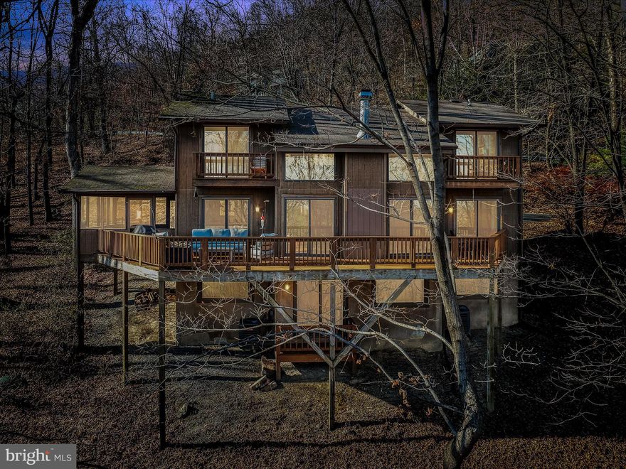 SALE INCLUDED ADDITIONAL LOT
Nestled on one of the most coveted lots in Coolfont, this home offers serene mountain views and privacy, surrounded by acres of lush trees. Designed for both relaxation and entertaining, this 5-bedroom, 5-bathroom chalet is a haven of comfort with views from every room.
The home has been lovingly maintained and thoughtfully updated, featuring hickory flooring on the upper two levels, new luxury vinyl plank flooring on the lower level, and freshly stained decks and front steps. The modern kitchen boasts quartz countertops, stainless steel appliances, including a double oven range, dishwasher, and refrigerator, as well as an updated sink and faucet. A new washer and dryer provide added convenience on the lower level.
The open-concept design flows seamlessly from the kitchen and dining area into a soaring two-story great room with a cozy wood-burning fireplace. Each of the five spacious bedrooms (two upper, two lower, primary on the main) has its own ensuite bathroom, while the main-level primary suite includes a jacuzzi tub. Upper and main level bedroom open to private decks, perfect for enjoying the peaceful mountain surroundings.
The lower-level recreation room is ideal for games, media, and gatherings, with 2 bedrooms located on this level as well as the laundry and utility rooms.  While the screened-in porch provides a quiet spot to take in the views. Outside, a charming rock garden filled with heirloom irises, lilacs, daffodils, and more adds character to the property.
This energy-efficient home features two-zone HVAC systems and water heaters for year-round comfort. With abundant closets and storage throughout, it’s as practical as it is beautiful. The property has never been rented and comes partially furnished, including a stylish sectional sofa, beds, recreation room furniture (complete with a foosball table), and more.
Coolfont Mountainside offers community amenities such as a pool, playground, and year-round social activities. Just down the road, Cacapon State Park provides an array of outdoor activities, including hiking, biking, and swimming. The nearby Coolfont Resort adds to the appeal with a fantastic restaurant, pickleball courts, a fitness center, and a swimming pool.
Sellers are offering the opportunity to purchase the adjacent vacant, buildable lot #9 at a reasonable price for additional privacy.
Whether you’re seeking a full-time residence or a weekend getaway, this home is a perfect choice with an easy commute from the DC area, Philadelphia, and Baltimore. Schedule your showing today to experience the ultimate in serene mountain living! 
Please visit coolfontmountainside.com for lots of great info on the community including covenants & restrictions, w/s info, contacts, news, details of events, amenities and more!