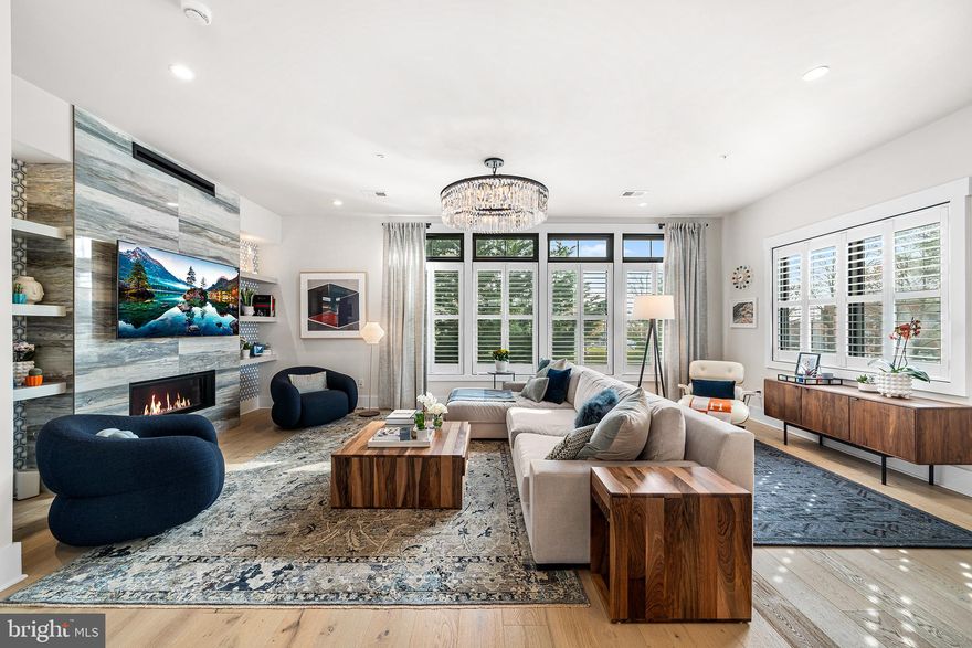 Discover the opportunity to own a breathtaking 3,400 sq ft stunning corner townhome in the prestigious Brownstones at Berkley, an exclusive community with only seven residences. As you step inside, a grand foyer leads to a versatile flex room, currently set up as a gym with a full bathroom. This level also offers easy access to the two-car garage through a large mudroom with plenty of storage. The main living area is designed for seamless entertaining, featuring 10-foot ceilings, an open-concept layout, and a spacious great room with oversized windows adorned with custom plantation shutters and custom lighting. A striking gas fireplace with built-in shelving completes the living area. The kitchen is a dream, featuring custom cabinetry, a massive double-sided island with abundant storage, high-end quartz countertops, JennAir stainless steel appliances, and elegant custom pendants over the island. Adjacent to the kitchen, you'll find a coffee bar with a beverage refrigerator and extra storage. The dining area, ideal for hosting large dinners, complements the space. A few steps up is a beautifully appointed powder room featuring custom wall paper and additional storage. On the next level is the luxurious primary suite, offering ample space for a king-size bed, a large walk-in custom closet, and a spa-like en-suite bathroom with a double-sink vanity, a frameless glass walk-in shower, gorgeous tilework, and a separate water closet. The front of the home features two spacious bedrooms each with custom closets, a hall bath for the two bedrooms to share, and a laundry room. The top-floor offers even more living space, currently set up as a home office, with a half bath, wet bar with beverage refrigerator, and custom closet. This room opens up to the private rooftop terrace complete with an outdoor kitchen and stone fireplace for ultimate comfort and functionality. Additional highlights include a 4-stop elevator for easy access to every level, gleaming wood floors throughout,  custom carpet runners, designer wallpaper, custom closets, elegant lighting fixtures, custom window treatments, Sonos, and plentiful storage throughout.  Enjoy easy access to upscale restaurants, the R-5 train, fantastic shopping in downtown Wayne, Whole Foods, coffee shops, gyms, and so much more.  Come check out this immaculate home today!