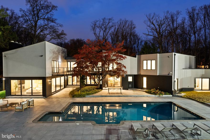 Tucked away on a private cul-de-sac within the prestigious Windermere neighborhood of North Bethesda, this fully gated modern estate is a rare expression of scale, privacy, and refined design. Offering more than 10,000 square feet of living space and extensively renovated in both 2018 and 2022, this residence delivers a seamless blend of architectural elegance and advanced technology. From the moment of arrival, the home makes a striking impression with a custom, oversized glass-front door opening to a dramatic two-story foyer that sets the tone for the light-filled interiors. Inside, soaring ceilings and expansive walls of glass create a seamless connection between indoors and out, highlighting the sleek modern design and heated ceramic tile floors that reinforce a sense of enduring quality throughout.

The main level unfolds into a series of beautifully proportioned rooms designed for both grand entertaining and comfortable everyday living. An oversized family room anchors the space with two walls of windows and a gas fireplace, while a nearby sunken living room offers a more intimate setting framed by large windows. The elegant dining room provides a perfect backdrop for formal gatherings, complemented by a private office for quiet productivity. At the heart of the home, the chef’s kitchen serves as both a visual centerpiece and a functional hub, featuring dual quartz waterfall islands and custom Cabico cabinetry. This culinary space is equipped with professional-grade Thermador appliances, an oversized walk-in pantry, and a sunlit breakfast area that overlooks the pool.

The upper level is designed as a peaceful retreat, anchored by an extraordinary owner’s suite that includes a spacious sitting room with its own gas fireplace and a private balcony overlooking the backyard. The spa-inspired bath features heated floors, a soaking tub, an oversized frameless glass shower, and dual skylights that flood the space with natural light. Additional bedrooms on this level are equally well-appointed, including a second primary-style suite and several en-suite bedrooms with designer finishes and thoughtful window seats.

The fully finished lower level expands the lifestyle offerings of the estate, serving as a destination for wellness and recreation. It features a sophisticated lounge with custom cabinetry, a state-of-the-art theater room with soundproofed walls and reclining seating, and an oversized professional-grade gym with mat flooring and a full bath. Outside, the property transforms into a private resort centered around a heated swimming pool and spa. An expansive limestone patio provides ample space for relaxation, while a fully equipped outdoor kitchen enables effortless al fresco dining. The grounds also feature a lighted sport court for basketball or tennis, all enclosed by high-end privacy fencing and lush landscaping.

One of the estate’s most exceptional features is the climate-controlled seven-car garage, which includes a fully self-contained private apartment. Accessible through both interior and exterior entrances, this space features a living room, kitchenette, private balcony, and a luxurious bedroom suite, making it ideal for guests or live-in accommodations. The entire home is fully automated with a Savant smart home system, providing seamless control of lighting, climate, and security. This Windermere estate offers an extraordinary lifestyle where luxury, technology, and tranquility exist in perfect balance.