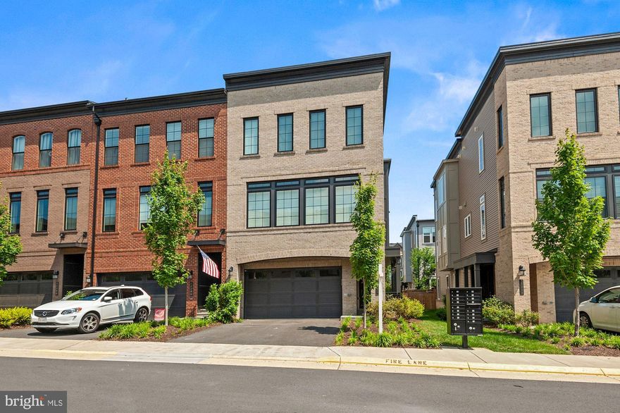 Just a couple blocks to  the Brambleton Town Center, this quality-built Miller & Smith end unit could be yours!   Contemporary, open floor plan with engineered wood floors and custom wood shutters.   Built in 2019, this grand home lives large without the upkeep of a single family.   Why even the yard is taken care of by the HOA!  
Gorgeous and on-trend white kitchen with super-size island and bar seating on two sides, abundant cabinetry, gas cook top and stainless appliances.   There is even a dedicated serving area flanked by two closets/pantries for those fun parties you'll have.  On either side of this awesome kitchen are two flexible rooms - but remember, this is an open floor plan and you choose what goes where!   It could be a dining room on one side and a family room on the other.  Or an office or perhaps you want more entertaining space....you choose.   The glass doors open to the mid-level deck.  This model (the Norland) rapidly sold out during construction, and it's easy to see why.    There's an ease to living here because there are very few walls on the main level -- just relax and feel the s-p-a-c-e.   Upstairs is a bit more traditional -- it's the bedroom level so of course privacy is needed here and once again the floor plan delivers.  On one side is the owner's suite with a huge walk in closet and luxury bath.   The bathroom has a decadent shower with rainfall head, oversized vanity with double sinks and private water closet.    Down the hall and on the other side of the laundry room, there are two more bedrooms - each with en-suite bath and a walk in closet.   The laundry room has a sink and a linen closet.   Retracing steps to the entry level, you'll find a large flex room with a gas fireplace as the centerpiece.   Full glass doors lead to the fenced backyard.  It is perfect for little ones and furry family members.   
The location is phenomenal in the center of Brambleton.  Spontaneously want to catch a movie or grab dinner?   Date night is at your door step.   FIOS internet and cable, trash and recycling, lawn care, snow removal are included in HOA dues.  Enviable community amenities include multiple swimming pools, parks, walking paths, library, pop up concerts, pool parties and swim club, tennis, basketball and volleyball courts, summer camp, craft programs and community events.  Quick move in possible.  Why wait?  Call your agent now.