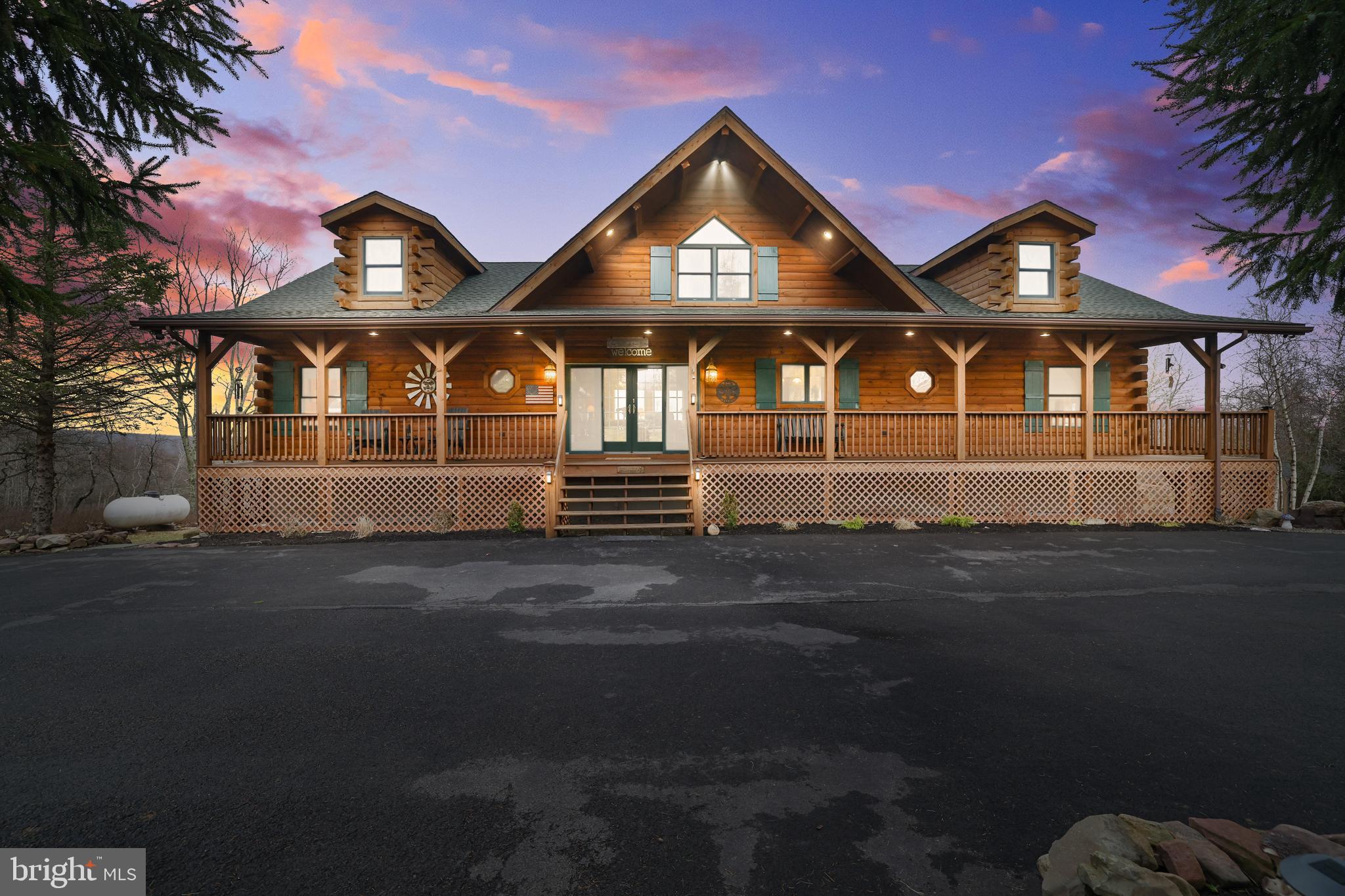Welcome to your dream escape in the heart of the Poconos! This stunning 3-bedroom, 3-bathroom modern log cabin blends rustic charm with refined finishes across more than 3,100 square feet of thoughtfully designed living space. Nestled on a beautifully landscaped 2-acre lot, this home offers privacy, serenity, and panoramic views—including Blue Mountain on clear days! Step onto the expansive full-length front porch, or entertain in style on the over 850-square-foot back deck that overlooks the rolling valley—an ideal space for gatherings, dining al fresco, or simply soaking in the beauty of the great outdoors. The property features a circular driveway leading to a 2-car garage, wrapping around for effortless access. You'll also find a novelty pond, an organic garden, and a newer greenhouse—perfect for gardening enthusiasts and nature lovers alike. Inside, the wow factor begins the moment you enter through the sliding doors. The soaring ceilings and wall of windows in the great room immediately draw your eye to the spectacular views. Anchoring the space is a stately stone propane fireplace and a beautifully crafted mantel—this room is truly a showstopper. The eat-in kitchen features rich cabinetry, granite countertops, a stone-accented peninsula, and stainless steel appliances with gas cooking. Whether you're sitting at the peninsula or in the adjacent dining area, every meal comes with a view. The main floor offers two spacious bedrooms, an office, and two full baths, including a secondary suite with a luxurious soaking tub, stall shower, built-in dresser, and private access to the back deck—imagine waking up to breathtaking views every morning. You'll also find a laundry room and walk-in pantry conveniently located on this level. Upstairs, a sunlit loft space offers over 300 square feet of flexible living overlooking the great room. There is also additional access to wonderful storage space. Downstairs, the primary suite is your private retreat, complete with sweeping backyard views, a private patio, electric fireplace, custom luxury bath, and an oversized walk-in closet. This level also includes a smart artic entry from the garage - keeping the cold out on winter days and ample storage space throughout. Craftsmanship shines in every detail of this unique home. Select furnishings may be included - ask for the list! Don't miss this rare opportunity to own a one-of-a-kind mountain home with both style and soul. Schedule your private showing today!