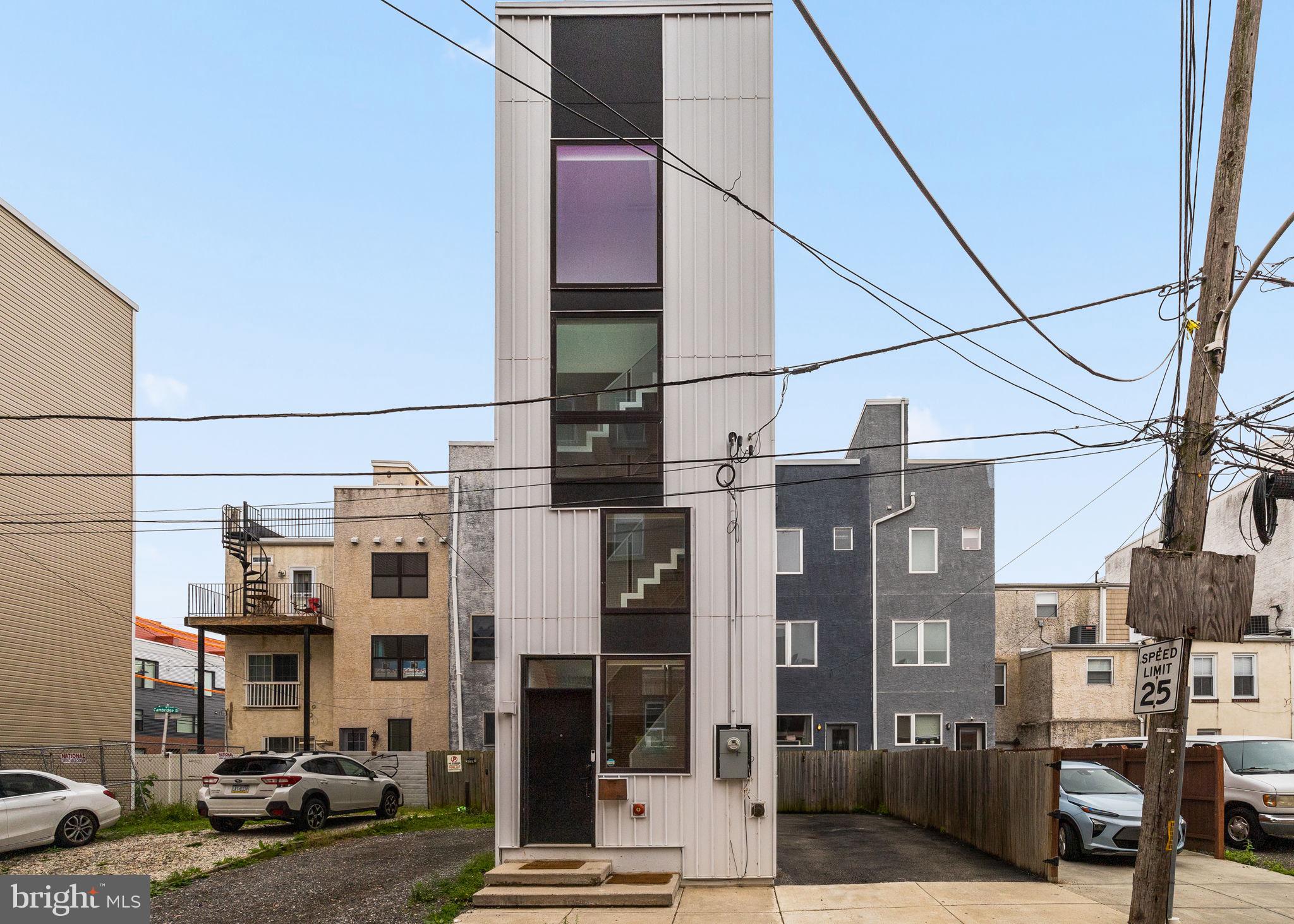 Step into an architectural marvel in the heart of Brewerytown. Tiny Tower—designed by ISA Architects, featured on NBC Open House, and recipient of the 2019 AIA Housing Award—is a trailblazing home that maximizes a mere 12′ × 29′ footprint into six levels of inspired living, totaling 1,250 sq ft. Highlighting vertical living at its best—this 38‑ft tall “mini‑skyscraper” follows the classic Philadelphia trinity-house vernacular, extended into a modern, five-story marvel atop a lower-level basement. Innovative folded‑plate steel stair—a striking feature on the front façade floods the home with light and creates a dynamic circulation “gallery”.
Designed for flexible living—each floor offers a single, open room: kitchen, living, office, bedroom, master suite, all crowned by a private roof deck. Modern Scandinavian finishes—airy interiors with light-stained wood floors, crisp white walls, metal-clad wood windows, and metal siding outside create a clean, minimal aesthetic. Outdoor spaces at every level—a sunken garden in the terrace level, a walk-out second-floor terrace, plus a full rooftop deck offer rare city dwelling outdoor access. Urban convenience meets modern design— this 2‑bedroom, 2.5‑bath single-family home offers rare 2‑car driveway parking, set back quietly from Girard Avenue yet steps from Brewerytown’s vibrant restaurants, parks, and transit.