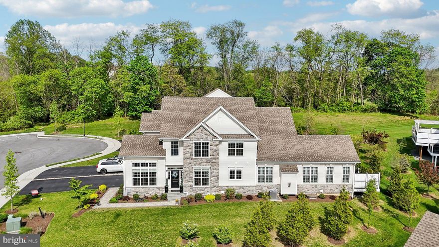 Welcome to 207 Reid Way in the luxurious community of Darlington Ridge. This spacious Bucknell model end unit has many original structural upgrades including an expanded great room, Sarasota Sun Room addition, expanded rear deck, the study and home office option just off the foyer, two primary suites with ensuite baths both with shower and bath upgrades and so much more! Additional upgrades and improvements include sleek engineered hardwood floors that span the entire first level and second floor loft, fabulous custom lighting selections, designer window treatments, neutral paint colors, custom closets, plantation shutters throughout the first floor, and a partially finished basement with egress window and a rough-in for a full bath. The gourmet kitchen is the true focal point of this home and appointed with upgraded white Century Cabinetry, stunning quartz countertops, a beige and cream subway tile backsplash with grotto design on the angle, an expanded island with additional seating and storage, large pantry, a classic wet bar with glass cabinetry above, under and over cabinet lighting and an upgraded stainless steel appliance suite that includes a 5-burner Jennaire cooktop, wall oven with microwave combo and dishwasher. The kitchen flows into the expanded family room featuring a vaulted ceiling and gas burning fireplace with a wood mantle and slate surround. The adjacent sun room is surrounded by windows and provides a beautiful space for an owner with a green thumb preference, reading habit or alternate home office. Enjoy the luxury of main level living with a first floor owners suite complete with a tray ceiling, large walk-in custom closet, and beautiful en suite bath appointed with high end tile selections including radiant heated floors, an expanded  frameless glass shower with a long bench seat, comfort height dual vanity and water closet. The large low-maintenance rear deck includes a pergola on one section providing some shade and an adjacent section perfect for enjoying views of the sunrise and open space leading to the property tree line. Steps down to the open space allow for easy dog walks and play. Can’t forget the soaring 2-story foyer bathed in natural light from floor to ceiling windows. Step into your 1st floor study and home office through glass French doors for privacy and a quiet work space. The two story dining room is perfect for family and holiday dinners and entertaining friends. A convenient half bath and first floor laundry room is just around the corner as well as access to the 2 car garage with ample storage. Ascend the turned staircase to an open and airy loft space with more engineered hardwoods. Bedroom two is rear facing and has been upgraded as a second primary bedroom with a walk-in closet and ensuite bath with a dual vanity, soaking tub and walk in shower. Bedroom three is just down the hall and has more ample closet space and interior access to a full hall access bath with more upgraded tile and vanity selections. The basement has been finished as an open room with drywall, upgraded trim and two panel doors throughout. One half of the finished area has been finished as a fitness gym including specific padded gym flooring as well as having plenty of LED lighting throughout. The plumbing rough in is framed in and ready for another full bath. The builder also installed an egress window to allow for a future bedroom and more flex space. Two separate unfinished storage areas allow for plenty of storage. This upgraded and expanded floor plan is ONLY available in end unit home sites. Darlington Ridge is an active community and also includes over 80 acres of open space and miles of walking trails that stretch down Tigue Road and into the town of West Chester. 207 Reid Way is conveniently located just minutes from downtown West Chester, known for its vibrant community, offering fine dining, boutique shopping, incredible holiday celebrations, history, and excellent schools.