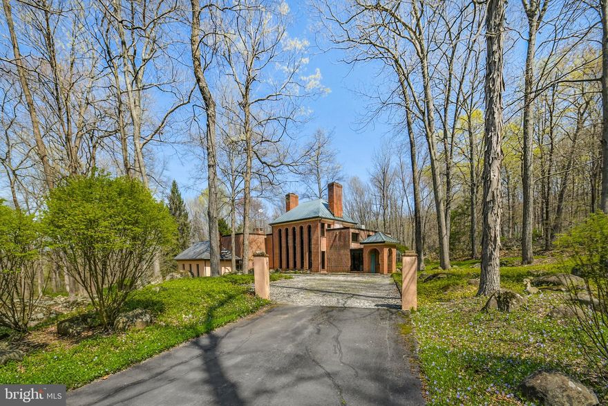 A sun-dappled lane bordering Cooks Creek is the approach to this stunning brick home nestled in the woods in Springfield Township. With two parcels totaling just over 14 acres, Spring Woods is a private rural sanctuary. 

Completely remodeled in 1996, this custom-built home has a 12” concrete block foundation and brick exterior on all 4 sides. Terra cotta tile floors with radiant heat welcome you into the entry room and continue into the kitchen and dining area with soaring ceilings, floor-to-ceiling windows, and two fireplaces. An open-air pantry, half bath and small greenhouse complete this level. A half flight of stairs leads down to the living room with slate floor, with office space just around the corner. Open steel stairs with custom designed railings lead up to the spacious primary suite with abundant windows, radiant heat floor, large tiled bathroom and multiple walk-in closets. The guest room is inviting with an ensuite bath and windows that look out over the stream that runs by the house. 

Perfectly positioned to take advantage of its natural surroundings, Spring Woods is a truly unique home that marries form and function for an unforgettable experience.