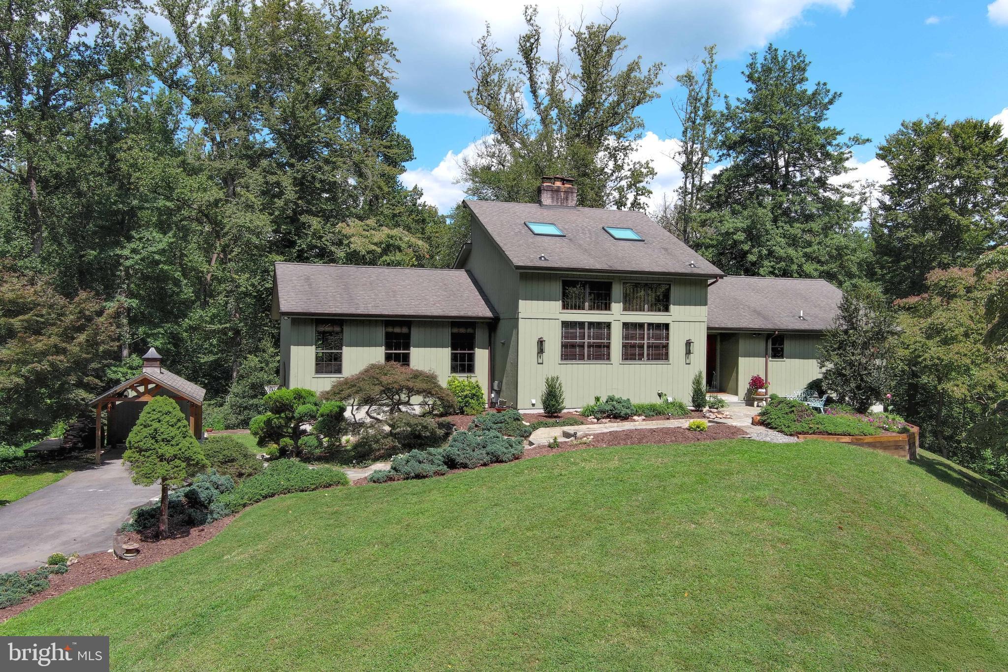 Set on more than 10 private acres in the sought-after Moyaone Reserve of Accokeek, Maryland, this meticulously crafted custom-designed home by Swedish master builder, Lennart Larson, blends timeless design, thoughtful details, and a lifestyle surrounded by nature. Six-inch walls provide excellent year-round insulation and the home’s southern exposure is perfect for passive solar heat in colder months. Offering 4 bedrooms plus loft, 3 full baths, a large screened-in porch and deck, a finished basement, 3 fireplaces, a two-car side-load garage plus an additional carport/covered pavilion and two sheds. With over 3,000 square feet of living space, this property has been lovingly maintained by its original owners and is now ready to welcome its next chapter. MAKE SURE YOU CLICK ON THE VIRTUAL TOUR LINK TO VIEW THE VIDEO OF THIS MAGNIFICIENT PROPERTY.
The home’s centerpiece is a breathtaking two-story GREAT ROOM with new red oak floors and an arched natural rock backdrop with an efficient soapstone stove. The wood stove easily converts to a charming fireplace. Opening to a newly updated deck, is a cozy, screened porch with a stone-front wood burning fireplace that overlooks the forest below. The gourmet eat-in kitchen features custom quartzite countertops, updated GE Café Series stainless steel appliances including a 5-burner range, refrigerator, built-in microwave and dishwasher. Abundant natural light is provided by a dramatic two-story wall of windows. The PRIMARY BEDROOM is located on the main level and features new hardwood floors and an ensuite renovated bathroom with dual sink vanity and refinished shower. The basement offers an updated full bathroom and fabulous laundry room with granite countertops and plenty of shaker cabinets. A large FAMILY ROOM with wood-burning Franklin stove completes the basement.
Continuing upstairs to the third level, a 4th bedroom with skylights and a separate living area makes an ideal guest suite, art studio, or private retreat.
Additional highlights include solid wood doors, custom beams in the ceiling, skylights, three wood-burning fireplaces (family room, basement, and screened porch), a two-car side-load garage, covered pavilion/carport, two sheds, and a deck with a retractable awning. Seasonal Potomac River views allow you to see the Washington Monument, National Harbor and festive fireworks from Mount Vernon.
With 10+ acres (well above the 5-acre minimum in Moyaone), the property may allow for subdivision or construction of a second home—providing unique long-term value.
The Moyaone Reserve is a historic, conservation-focused community preserving the Mount Vernon viewshed and offering unmatched access to nature. Residents enjoy boardwalks, kayaking in Piscataway National Park and community amenities such as an outdoor swimming pool offering a swim team, community garden, playground, covered pavilion, grill pavilion, tiki bar, and gathering spaces. Voluntary HOA membership keeps dues very low while supporting amenities and road maintenance.
Despite its peaceful seclusion, the property is ideally located near Joint Base Andrews, National Harbor, Old Town Alexandria, the Pentagon, National Landing, and Washington, D.C. Only 30 minutes outside of Washington, DC, this is more than a home—it’s a mountain-like retreat and an opportunity to own a rare piece of one of Maryland’s most sought-after communities.