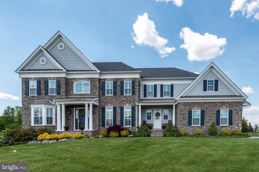 This absolutely stunning home in desirable Estates at Mill Creek Ridge, is only 3 years old and better than new! Experience the relaxing rural feel with views of horse farms while still being conveniently located just 10 minutes from Doylestown, 15 to Newtown and New Hope for your choice of shopping, dining and culture. The stone façade, front porches, columns and double front doors make for exceptional curb appeal. Once inside, you will love the gracious foyer with straight back views of the rear grounds as in the old-style Bucks County Manor houses. So refreshingly different from the traditional colonial! To each side of the foyer are the living and dining rooms showcasing the upgraded trim package throughout. Step through the dining room to the butlers pantry with rows of cabinets & counters to store dinnerware and have dishes and beverages stand ready for serving. Around the corner is the heart of the home encompassing the amazing gourmet kitchen, eating area and family room. With the walls of windows, the open space is light and bright even on the cloudiest of days. The gourmet kitchen is the place to create while entertaining family & friends seated at the counter. And the creating is easy with the upgraded Jenn-Air appliances and 6 burner stove with double ovens plus wall ovens! Have to do some work? There is a wonderful computer room adjoining the kitchen – perfect for managing the bills or homework for the kids. Working from home today? Tucked away in the rear corner of the house is a lovely, peaceful  office with beautiful back yard views. Choose the main staircase or the rear stairs off the kitchen to access the second level. The elegant main suite has a lovely sitting area, luxurious bathroom with freestanding soaking tub, frameless shower, makeup vanity and private commode. The walk-in closet has a large packing island! All three spacious additional bedrooms feature private bathrooms and walk-in closets. A convenient laundry room completes the second floor. Gather for relaxing fun in the finished walk-up lower level which features a wet bar, TV area, bedroom/playroom/office space, full bath and exercise area. Exit to the wide-open, fully fenced back yard with a wonderful playset and in-ground trampoline! Don’t miss your opportunity to see this fabulous home – make your showing appointment today!