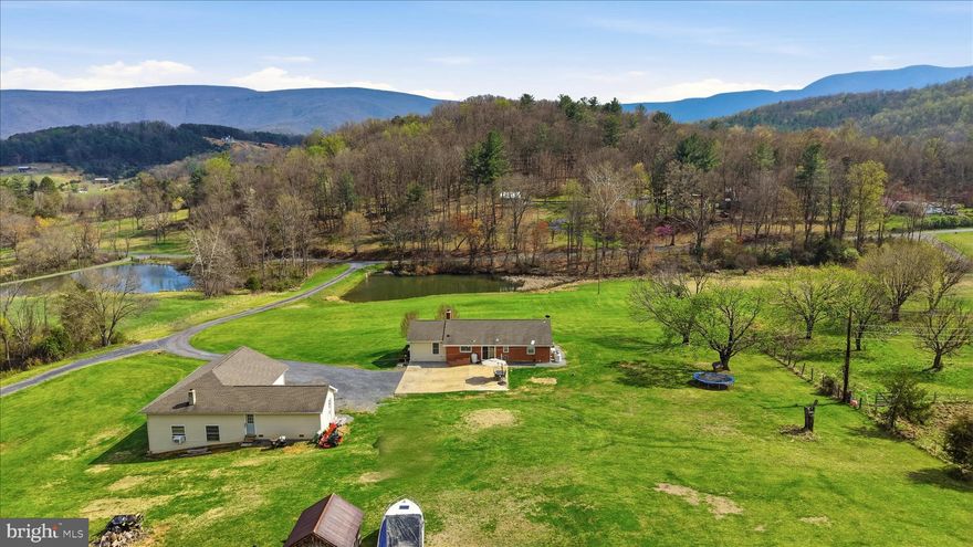 Welcome to 4001 Bentonville Rd in Bentonville, VA—where comfort, space, and thoughtful upgrades come together in a beautiful brick ranch home set on 5 scenic acres with mountain views and a spring-fed pond.
This well-maintained home offers 4 bedrooms (3 bedroom-6 person max occupancy, conventional septic) and 2 full bathrooms, with a layout designed for both everyday living and flexibility. A thoughtfully designed addition creates a split-bedroom floor plan, ideal for added privacy. The addition is equipped with efficient mini-split systems for year-round comfort, while the main home is serviced by an HVAC system that was replaced approximately 1.5 years ago and includes a U/V light filtration feature.
The main level features gleaming hardwood floors and a welcoming living room centered around a classic brick fireplace with hearth, mantle, and charming sconce lighting. The large eat-in galley kitchen offers great functionality with newer appliances, including a refrigerator with the large glass front, cooktop, and microwave—all less than 4 years old.
The primary bedroom offers 2 large cedar lined closets. Main-level bathroom was recently renovated (approximately 2 years ago) showcasing stylish tile flooring, a beautifully tiled shower with built-in bench seating, and a double vanity. Downstairs, the finished basement adds valuable living space and includes a second full bathroom.
This property is packed with additional upgrades for comfort and peace of mind, including a whole-house water filtration system with U/V light and softener through Water Works, a radon mitigation system, Generac generator, and a newer roof on both the home and garage (approximately 5 years old).
Car enthusiasts, hobbyists, or those needing extra workspace will appreciate the impressive detached garage—approximately 40’x30’ plus additional storage space. It features a 13’ tall door, wood stove, three 220-V outlets, and an exterior RV plug. A 14’ lift can convey with an acceptable offer.
Enjoy the beauty of nature right from your own front yard, with open acreage, mountain views, and a peaceful pond fed by a natural spring. This property offers the perfect blend of rural charm and modern convenience—ready to welcome you home