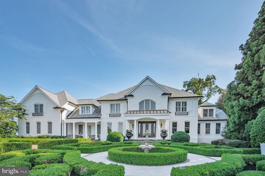 Gracefully sited on over 3 manicured acres inside Leesburg’s prestigious Beacon Hill community, this distinguished French Eclectic residence offers more than 11,000 square feet of exceptionally updated living space. From the grand foyer to the resort-style pool and pavilion, every detail has been thoughtfully curated to blend timeless design with modern luxury crafted for both grand entertaining and everyday elegance. A sweeping staircase and custom millwork set the tone in the grand two-story foyer, leading to formal living and dining spaces, a richly paneled study, and a light-filled family room with expansive views of the private grounds. The home showcases fine finishes throughout, including herringbone-pattern hardwood floors, artisanal millwork, soaring ceilings, designer lighting, and classic architectural details.
The chef’s kitchen is a statement in both style and function—featuring commercial-grade appliances, a farmhouse sink, elegant quartz countertops, a walk-in pantry, and a generous island. Upstairs, the executive primary suite offers a fireplace, dual walk-in closets, and a spa-inspired bath. Four additional bedrooms and three full baths provide comfort and privacy for family or guests.
The fully finished lower level features a spacious recreation room, custom wet bar, and dedicated theatre room perfect for hosting or relaxing at home.
The resort-style oasis is a true retreat, complete with a heated pool, elegant pavilion, stone fireplace, and multiple seating areas designed for year-round enjoyment and entertainment. A sports court and professional landscaping complete this special outdoor setting.
This estate is a rare offering that combines privacy, scale, and timeless sophistication in one of Loudoun County’s premier communities.