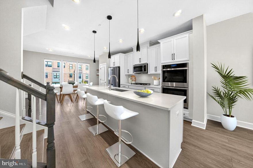 Built in 2023, this stunning brickfront 3-bedroom, 3 full, 2-half-bath townhome offers over 3,100 square feet of elegant living space, a rooftop deck, and an array of upgraded features in the sought-after Gateway West community. Designed for modern living, this home blends style and functionality with an open-concept layout, abundant natural light, and high-end finishes throughout. The main level welcomes you with a spacious living area featuring luxury vinyl plank flooring, recessed lighting, and a cozy electric fireplace. The gourmet kitchen is the true centerpiece of the home—complete with stainless steel appliances including a gas cooktop, built-in microwave, and dual wall oven, complemented by upgraded white cabinetry with sleek black hardware. A massive center island anchors the space, perfect for casual dining or entertaining alongside the expansive dining area. Step outside to the low-maintenance composite deck, ideal for morning coffee or relaxing outdoors, with a conveniently located powder room nearby. Upstairs, the impressive owner’s suite offers a large walk-in closet and a spa-inspired en-suite bath with a frameless glass walk-in shower and dual-sink vanity. Two additional bedrooms share a full bath with a tub/shower combo, along with a conveniently located laundry room for added ease. The penthouse level serves as a true retreat, featuring a versatile flex space complete with a powder room and direct access to the stunning rooftop deck, ideal for a rec room or private home office. With no rear neighbors, the roof space provides a serene setting for evening stargazing or relaxing in the cold plunge. The light-filled ground level includes another flexible room with a half bath and garage access—perfect for use as a home gym, theater room, study, or formal sitting area. With three spaces to enjoy the outdoors, including the fully fenced rear yard with patio and green space, fresh air can be enjoyed from nearly every level. An attached two-car garage, complete with EV charging, and driveway accommodates parking for up to four vehicles. Ideally located less than one mile to Hyattsville Metro (green line) and short distance to University of Maryland, Mall at Prince George's, Downtown Hyattsville, and Arts District with options for entertainment, dining, and shopping. This is low-maintenance luxury living at its best—don’t miss it!