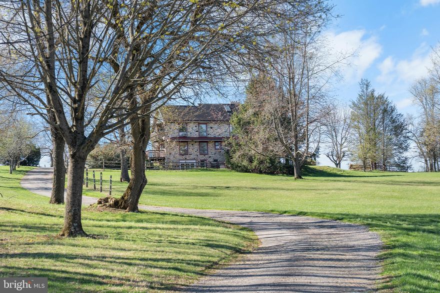 Set on approximately 5.6 private acres in the desirable Chester Springs area, 1728 Valley Lane is a distinctive stone-built residence offering 2,900+ square feet of living space surrounded by natural beauty and open land. The main home features three bedrooms with the potential for four full bathrooms, including three finished baths with stall showers—one on each level—and a spacious upper-level bath with a soaking tub that is accessible from both the hallway and the primary suite. A second-floor bedroom includes a framed-out bath ready for completion, offering additional flexibility. The main level includes a bedroom with direct access to a side deck, while the living room showcases random-width wood plank flooring and a wood-burning stove, creating a warm and inviting atmosphere. A galley-style kitchen connects to a sunken family room filled with natural light from expansive windows and offering easy access to the in-ground pool. Outdoor living is enhanced by multiple decks and a peaceful setting within a private community that includes a pond. Additional features include a detached three-car garage with workshop potential, an A-frame storage structure, and a separate outbuilding ideal for storage, office space, or recreation. Located within a highly regarded school district and offering a rare combination of acreage, privacy, and versatility, this property presents a unique opportunity for a buyer to personalize and elevate a truly special home.