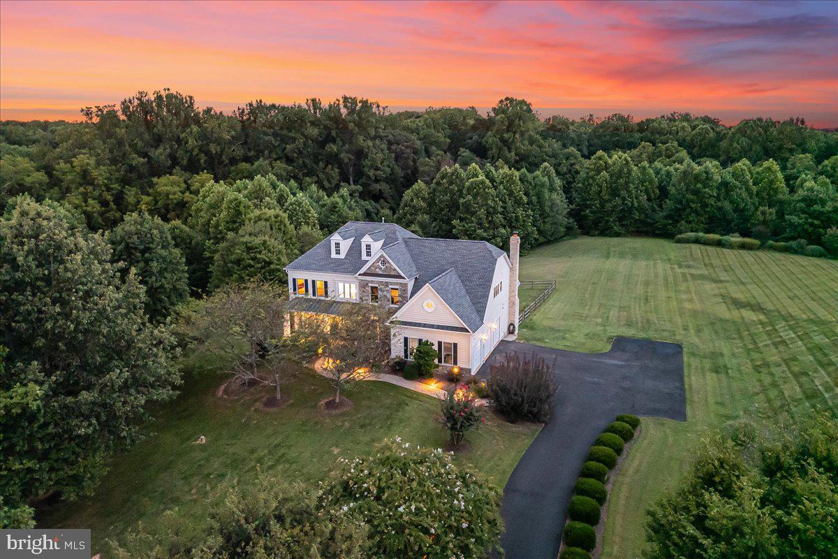 At the end of a quiet cul-de-sac in sought-after Brookefield, one of the area’s most peaceful and established neighborhoods, this 5-bedroom, 4 full and 2 half bath Colonial sits on 2 private acres backing to parkland, offering a rare blend of serenity, space, and convenience. With over 5,500 finished square feet, the home welcomes you with a dramatic two-story foyer and a sweeping curved staircase that sets a grand yet inviting tone. The main level features a sunny formal living room, a spacious dining room with crown molding, and a show-stopping two-story family room anchored by a floor-to-ceiling stone fireplace and pastoral views. The open kitchen, outfitted with stainless steel appliances, granite counters, a large island with seating, and a walk-in pantry, flows easily to the breakfast nook and outdoor entertaining spaces. Upstairs, the oversized primary suite is a true retreat, complete with a sitting area, two large walk-in closets, and a spa-inspired bath with soaking tub and dual vanities. Two additional bedrooms share a thoughtfully designed Jack-and-Jill bath, while the fourth upstairs bedroom enjoys the privacy of its own ensuite bathroom, ideal for guests or older children. The fully finished walk-out lower level includes a generous recreation area, a second kitchen, a legal bedroom with ensuite full bath, and an additional half bath, perfect for in-laws, an au pair, or guests needing a bit more independence. There’s also a large utility/storage room with a second washer and dryer and ample space for hobbies, workouts, or organization. Outdoor living is equally impressive, with a flagstone patio overlooking protected woods and Rock Creek Stream Valley Park. The attached three-car garage and extended driveway provide ample parking, while the lot’s placement offers privacy and stunning views in every season. Located within minutes of commuter routes, parks, and local attractions, this home is a peaceful sanctuary with everything you need close by. Welcome home.