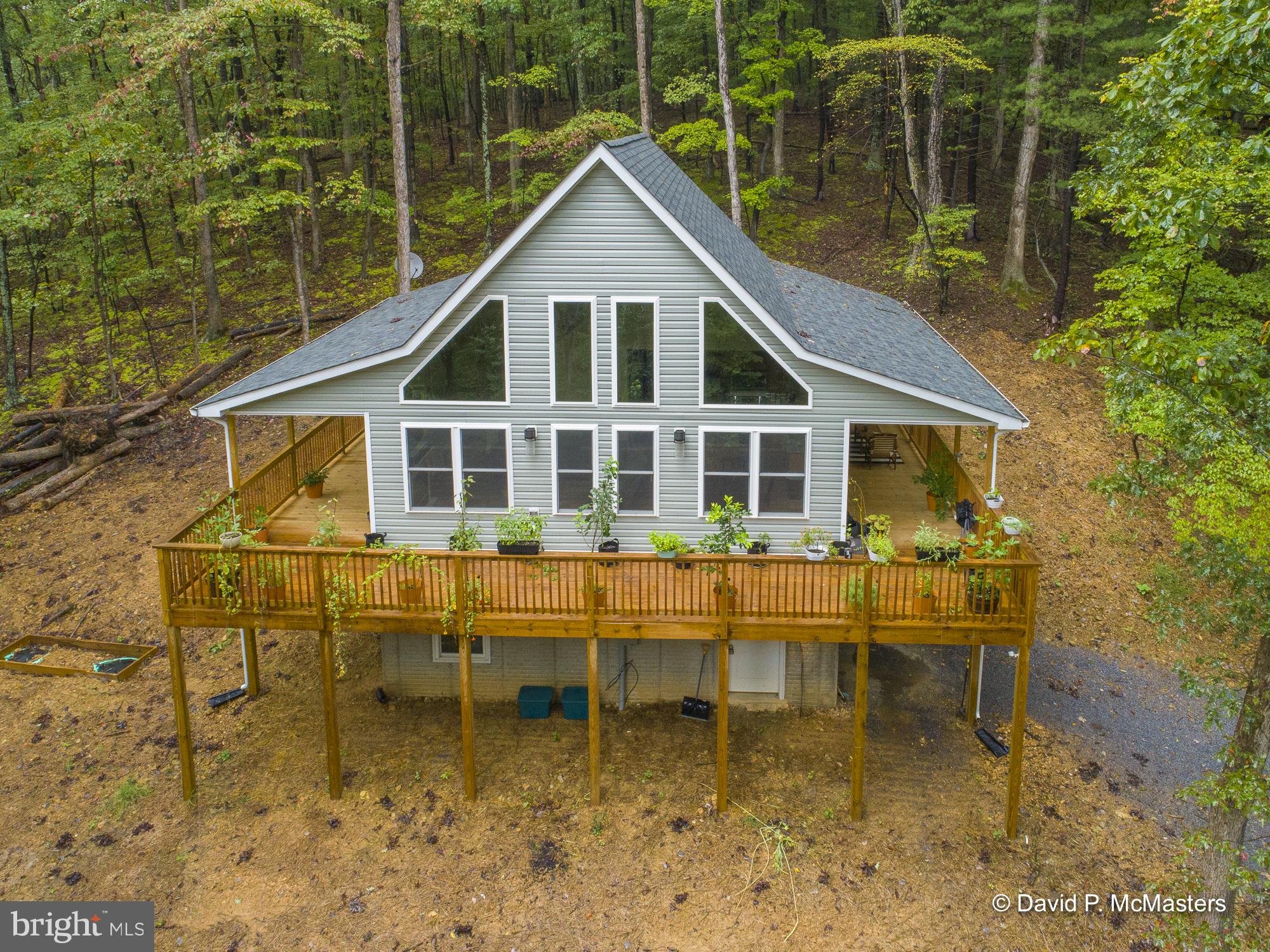 Multiple offers. Best and final due 9/29 5 pm. A Beautiful new - less than a year old - chalet on 5.23 wooded absolutely gorgeous acres. If you are looking for a retreat, it doesn't get much better than this home. There is a stream running through the property and the house is surrounded by huge old trees in a community of homes on large wooded lots so you don't see your neighbors. And it is a charming home with a large deck that wraps around 3 sides of the house. The roof extends over the deck on 2 sides so how great would it be to sit out there on a rainy day and just enjoy these gorgeous old trees. The deck is large enough for good sized patio furniture so you can create a nice gathering place for friends and family. Inside, there's a cathedral ceiling with huge windows to enjoy the view year round. There's vinyl plank flooring in the great room and a nice kitchen area with granite countertops and upscale appliances that convey. There's 2 bedrooms, one on the main level and one in the loft area - both with a private bath. There's a half bath and laundry room on the main level. There's a full basement and 1 car garage. Lakewood Acres is a beautiful part of West Virginia. The lake is available to residents for fishing and canoeing. I can't imagine a better place to relax and unwind. Home is not on GPS - directions are included in this listing. See floorplan for room sizes. Someone is going to get a wonderful retreat. Check out the tour for more information about the home and area.