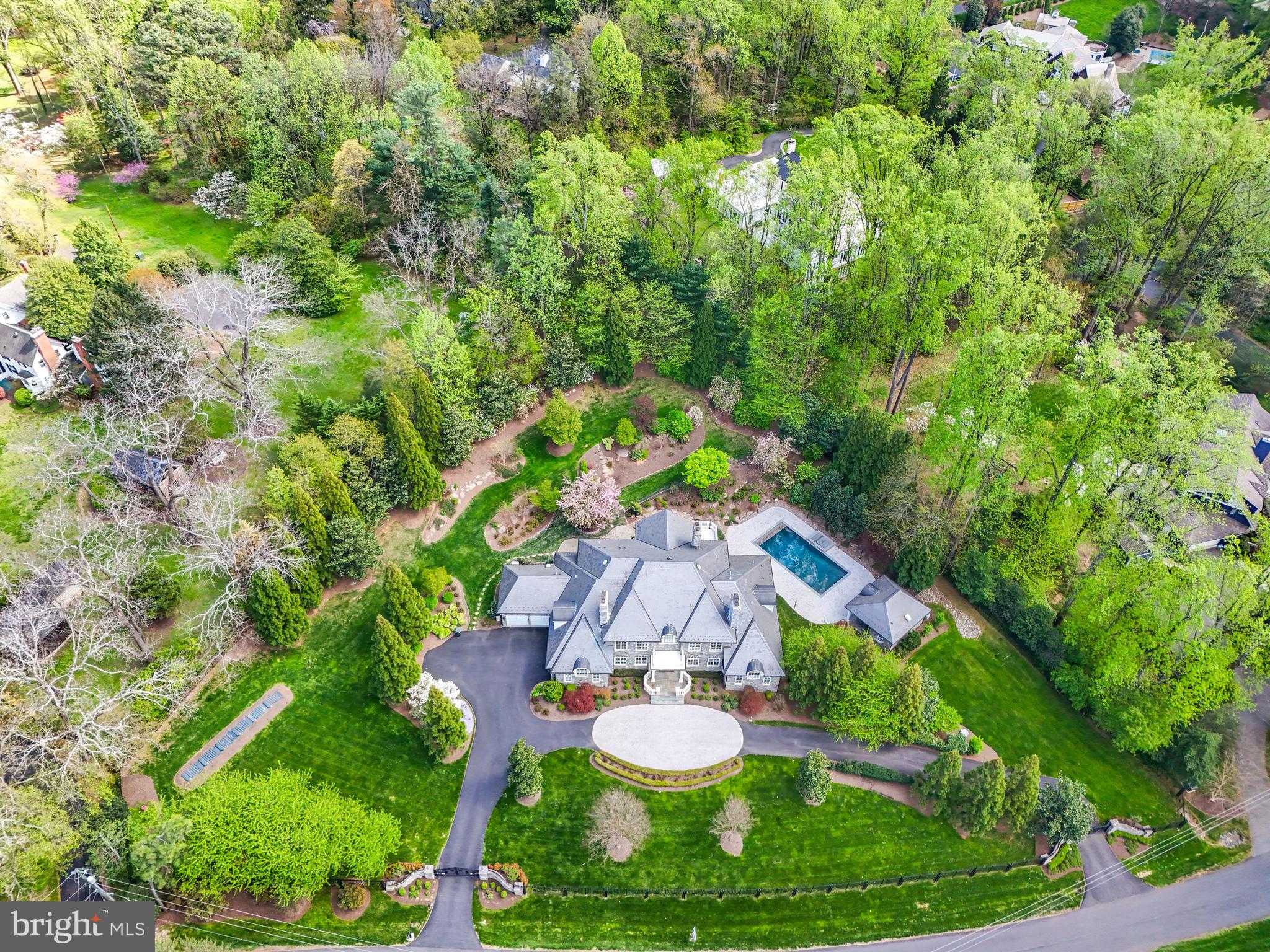 Welcome to 1221 Mottrom Drive. A Private Oasis in a Coveted Location. This spectacular estate, well over 12,000 square feet, is nestled in one of the area's most sought-after neighborhoods and crafted by renowned builder George Sagatov. Privately gated and set behind a circular driveway, the home makes an unforgettable first impression with its striking curb appeal, lush professional landscaping, and a sparkling resort-style pool. Step inside the grand two-story foyer, where a dramatic curved staircase sets the tone for the refined interiors that follow. The formal living room and banquet-sized dining room each feature their own fireplaces, elegant mantels, and arched doorways that add architectural charm. The heart of the home is the breathtaking great room with a floor-to-ceiling stone fireplace, coffered ceiling, and a wall of windows that flood the space with natural light and offer seamless access to the custom deck, perfect for indoor-outdoor living. The chef’s kitchen features custom cabinetry, a large center island, two dishwashers, a built-in coffee maker, warming drawer, and a work desk area. Also on the main level is a richly paneled private office with built-ins and a fireplace, as well as a spacious main-level primary suite with a walk-in closet and luxurious bath complete with separate vanities. Two powder rooms and a well-appointed laundry room complete the main floor.
Upstairs, the impressive owner’s suite is a true retreat with its own sitting room, fireplace, two generous walk-in closets, and a spa-like bathroom with separate vanities, soaking tub, and oversized shower. Three additional ensuite bedrooms provide comfort and privacy for family and guests. The walk-out lower level is an entertainer’s dream, featuring a fully equipped wet bar, wine cellar, state-of-the-art media room with tiered seating, a fitness room with sauna, a recreation room with stone fireplace, and an additional bedroom and full bath. Step outside to a true backyard paradise. The sparkling pool is complemented by a fully outfitted pool house with a full kitchen and bath, perfect for summer entertaining. Every detail of this home has been thoughtfully curated for luxurious living, all just minutes from the shops, restaurants, and commuter routes of Tysons Corner.