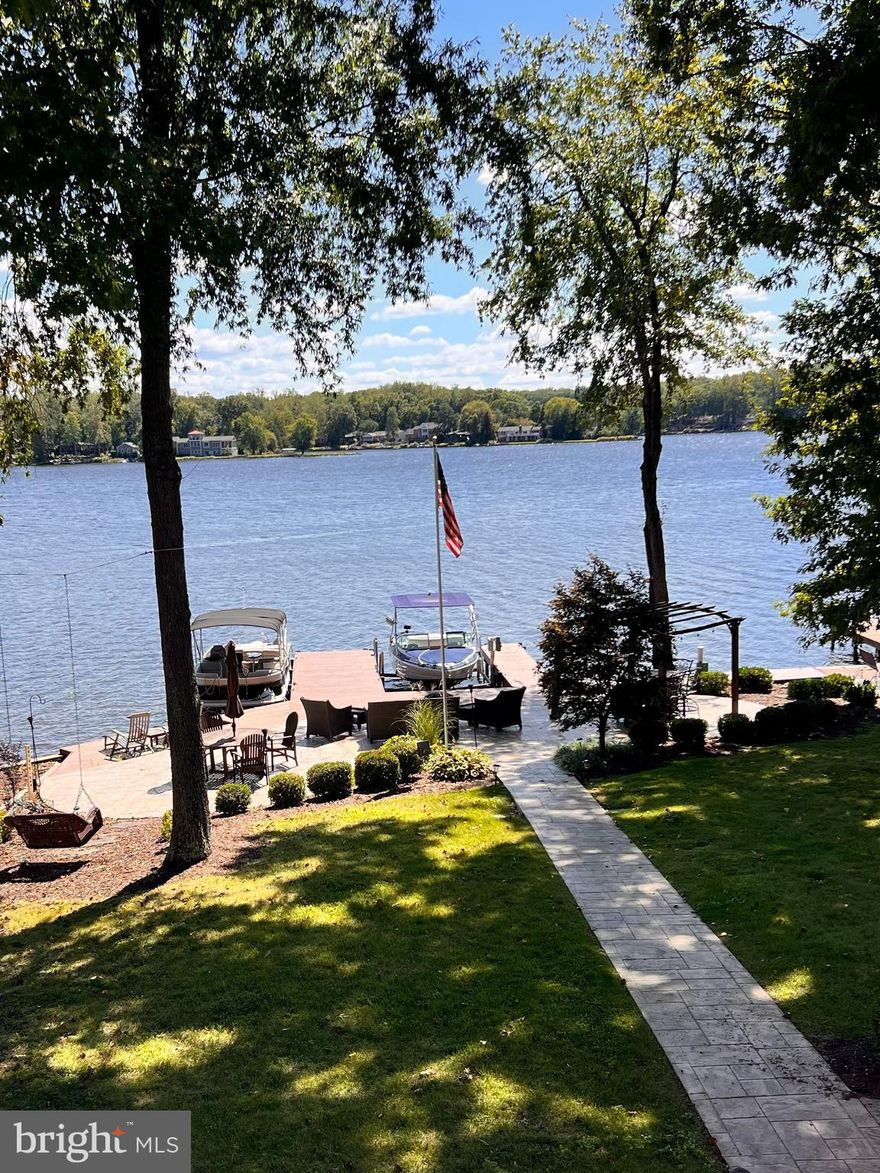 MOTIVATED SELLERS! Welcome to your dream lakefront retreat! This stunning 6-BD, 5.5-BA custom-built lakeside sanctuary offers the perfect blend of elegance, comfort, & waterfront living – located just 90 minutes from Washington DC & within 60 min from Richmond, Charlottesville, & Warrenton, VA. Perfectly situated for gorgeous lake views in one of the premier sections of Lake of the Woods-Virginia’s best kept secret-this 5602 square foot luxury home combines timeless elegance with modern comforts, offering both grandeur & serenity in a private, picturesque setting. As you step inside the main level, you’re greeted with open-concept living spaces, rich hardwood floors, & expansive windows in the family room framing breathtaking views of the water.
Thoughtfully designed for both everyday living & unforgettable entertaining, this custom-crafted home features a gourmet kitchen that is a chef’s delight, with a professional-grade Fisher & Paykel gas range, granite & butcherblock countertops, high-end stainless steel appliances, & a large island that flows seamlessly into the dining and living areas – ideal for hosting family holidays, summer get-togethers, or festive celebrations. The gas fireplace creates the perfect ambiance for evenings relaxing with the family or close friends. The main level also boasts a guest-suite with an adjoining bathroom & an in-home office.
The spacious primary suite on the upper level is a true oasis with large windows showcasing fantastic lake views from its expansive windows and private balcony. The spa-like master bathroom features a luxurious sauna shower, a jacuzzi soaking tub, dual vanities, & a large adjoining closet. The upper-level also contains a game-room & 3 additional bedrooms, including a Jack-and-Jill bathroom, & a beautifully-appointed guest room offering stunning lake views & comfort for special weekend guests.
On the lower level, this waterfront retreat showcases a fully-equipped in-law suite, with a kitchenette, expansive dining and family room, an oversized master bedroom, adjoining bathroom with a shower & dual vanities, and a laundry room and closet. The lower level provides a private living space with its own entrance, perfect for extended visits of family or guests, or even a rentable apartment.
This incredible lakeside home possesses not only an attached 3-car garage, large enough to house your vehicles & favorite rafts & other water toys, but also a detached single-car garage for additional storage, or for use as a workshop or for building the perfect man-cave.
Outdoor living is at its finest with multiple spaces to relax & take in the beauty of Lake of the Woods, starting with a private covered porch on the main level, ideal for both morning coffee & evening entertaining. Expansive front & backyards, complete with an irrigation system, provide ample space for recreation & relaxation. The newer lakeside patio & dock are fully appointed for entertaining, providing a beautifully-landscaped stage for swimming & sunning during the day, & then stargazing by the fire in the evenings. The dock features space for 3 boats and includes a high-capacity boat lift.
This lakeside retreat is fully-equipped & ready for boating, fishing, or simply soaking up the serenity of lakeside living. Furnishings & the two boats are negotiable, offering a very unique turnkey opportunity. This gated community offers resort-style amenities including beaches, parks, clubhouse dining, tennis & pickleball courts, an equestrian center, a state-of-the-art pool, fitness complex, & an 18-hole championship golf course.
Nestled in one of the most tranquil sections, this 2009 lakehouse provides stunning views and a peaceful setting. From evenings by the stone fireplace to days on the water, it captures the best of lakefront living—perfect for year-round enjoyment or a vacation retreat, blending comfort, style, and natural beauty.