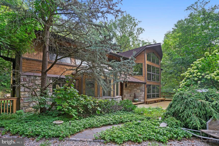 Looking for that one-of-a-kind, definitely, unique , custom built home surrounded by nature? This is a contemporary home with floor to ceiling windows to admire the scenery in every part of the house, no matter what the season. The sizable, wrap around deck was designed for that perfect indoor/outdoor living.
This accentuates, this beautiful home with views of Valley Forge Mountain. The original owner was an Artist in his woodworking and his craftsmanship. He drew his inspiration from Wharton Esherick whose nearby Homestead is a National Historic Landmark for Architecture. This open layout with 20 ft. ceilings and open beams are over the kitchen, breakfast area/dining area and the family room with a sunken fireplace pit. This floor to ceiling, stone fireplace boasts a gorgeous, hand crafted, inlaid wood flooring.
The fireplace with the floor to ceiling stone can actually heat the first floor. The family room is also open to the living room with another stone fireplace and multiple sets of sliding glass doors opening up to the massive wrap-around deck, for that indoor/outdoor feeling. The open kitchen area has a unique, circular, eating island. The solarium breakfast/dining area surrounded by windows and light, feels like you are eating outside. There's a 1st floor bedroom/office off of the living room. The 2nd floor is accessed by 2 staircases. There is a larger open wooden staircase and the Esherick inspired hand carved, spiral staircase. The original owner, inspired by Nature, saved a tree from construction and placed it artistically next to the spiral staircase. A fantastic, natural, focal point for the family room and the living room. The second floor main suite boasts, yet another stone fireplace, custom built bureaus and  cabinets, a large on-suite with double vanity, oversized tile shower and a jetted tub. There are 2 additional bedrooms and a hall bath. The main and 2nd bedroom each have their own loft area that overlooks the Great Room area, and the breathtaking, birds eye view of the sanctuary woods surrounding this home.  The 1 car garage is on the side of the home which enters into the kitchen. There is a full basement under the rear section of the home which could be the perfect, heated workshop, once used by the original owner. A large portion of the deck has been replaced, new stove, refrigerator, washer/dryer and trash compactor..
Need more space ? There is and additional building next to the main house that is over a 2 car garage that has been partially, renovated and has an additional bedroom, bath, living area and kitchen. Laundry area in the garage. This has all the makings of a great Art Studio or the perfect, quiet office. 
Don't miss this unique home in the woods with all that nature can show you at your own doorstep.