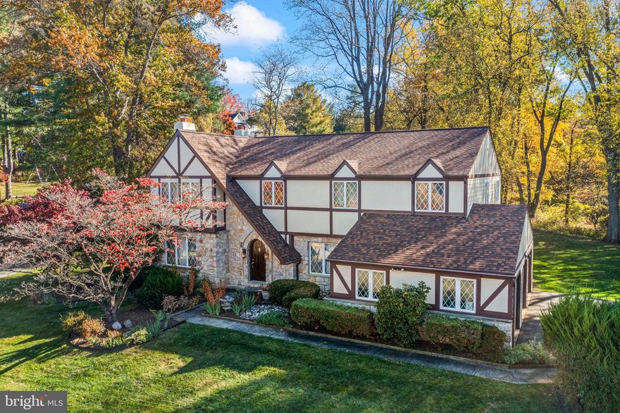 Welcome to 806 Northwinds Drive in the sought-after Radnor Chase neighborhood of Bryn Mawr—an exceptional Tudor-style residence offering over 4,000 square feet of beautifully designed living space in a premier Main Line location. Nestled within the highly ranked Radnor Township School District, this home combines timeless architecture, generous proportions, and a setting that’s simply hard to match.

A soaring two-story Entrance Hall creates a dramatic first impression and is flanked by a gracious Living Room with fireplace and an elegant Dining Room highlighted by large windows and abundant natural light. The rear of the home features today’s highly desirable open-concept layout, offering seamless flow and sightlines between the Kitchen, Breakfast Area, and Family Room—perfect for both everyday living and entertaining.

The Kitchen is appointed with warm wood cabinetry and granite countertops, opening directly to the inviting Family Room with its floor-to-ceiling stone fireplace. Just beyond, a spectacular Sunroom addition with vaulted ceiling and walls of windows provides panoramic views of the scenic rear yard and fills the home with natural light year-round.

The first floor also includes a stunning vaulted Office addition with built-ins on three walls, ideal for working from home; a spacious Mudroom/Laundry Room; a Powder Room; and convenient interior access to the three-car Garage.

Upstairs, the expansive Primary Suite offers a private retreat, complete with a Sitting Area (ideal for a second office or reading nook), a large walk-in closet, dressing table area, and a luxurious Primary Bath with deep soaking tub and separate steam shower. Three additional generously sized Bedrooms share an oversized Hall Bath.

The finished Lower Level provides remarkable flexibility, with multiple areas for TV and media, a game table, exercise space, and a separate room suitable for guests or an au pair. Abundant built-in shelving in the unfinished basement area and garage ensures exceptional storage throughout.

Outdoor living is equally impressive. Relax on the composite rear deck overlooking the picturesque yard, which adjoins neighborhood open space to the rear and right—offering privacy and a beautiful natural backdrop.

Recent improvements, including newer roof, windows, deck, exterior cladding, hot water heater, and HVAC systems, provide tremendous peace of mind.

Enjoy easy access to the shops and restaurants of Wayne and Bryn Mawr, nearby universities, train stations, medical and corporate centers, Center City, and Philadelphia International Airport. This is a rare opportunity to own a spacious, beautifully maintained home in one of the Main Line’s most desirable neighborhoods.
