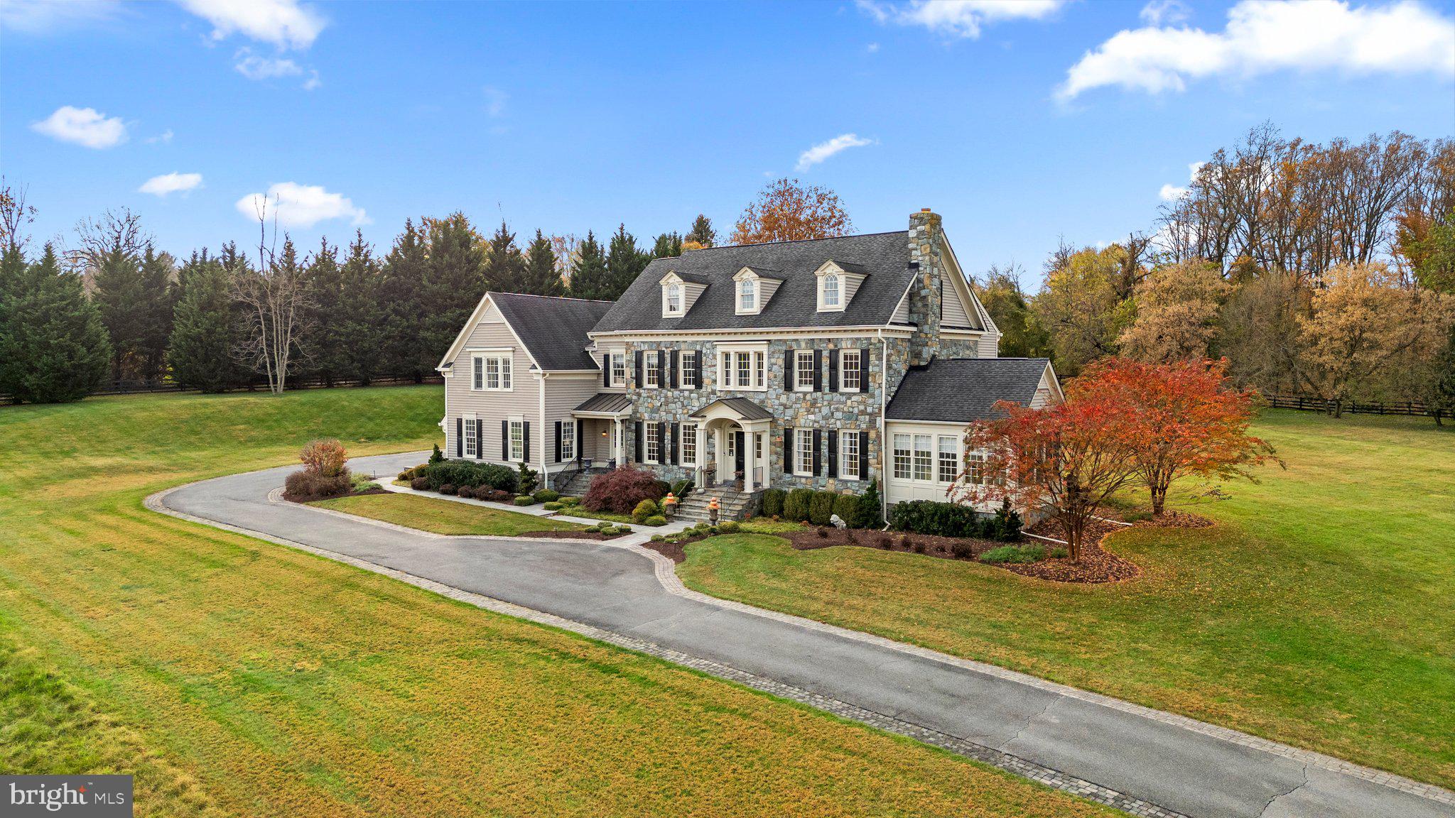 Welcome to a Dream Estate of Unparalleled Elegance and Serenity. Nestled on over 10 acres of breathtaking beauty in the prestigious Bancroft community of Sandy Spring, 17400 Ashton Green invites you to a life of luxury, sophistication, and tranquility. Positioned high on the property, this estate captures panoramic views of rolling landscapes and conservation areas from nearly every room, making it a rare treasure in this exclusive enclave of only 44 homes. The Eagles Nest, Mitchell and Best's largest model is designed to suit those who desire refined retreat-style living or the ultimate equestrian property. This extraordinary five-bedroom, five-and-a two-half-bath sanctuary spans over 9,000 square feet across four finished levels, displaying unparalleled craftsmanship in every detail. Stepping into the grand two-story foyer, you are immediately captivated by the exquisite detailing: from designer accent moldings to lustrous hardwood floors. An elegant, curved staircase sets a regal tone for the residence. Just beyond, double French doors open to a private home office, perfect for refined work-from-home days. The main level offers an abundance of spaces for both intimate gatherings and grand entertaining. The cozy living room, complete with a wood-burning fireplace, flows seamlessly into the formal dining room, while a sunlit, serene sunroom offers an ideal spot to enjoy nature views or relax with a favorite book. The gourmet kitchen is a chef’s paradise, designed with inspiration in mind. Equipped with top-of-the-line appliances, a central island with breakfast bar, custom backsplash, double wall ovens, and a six-burner gas range, it’s a space where culinary dreams come alive. This space opens to the family room, where wall-to-wall windows with built-in benches, a tray ceiling, and a cozy stone surround gas fireplace, invite warmth and sunlight, igniting the imagination with stunning views of the estate's vast landscapes. A private rear staircase ascends to the first upper level, where you’ll find the opulent owner’s suite with its tray ceiling, step-down sitting room, two walk-in closets, and a private balcony--a tranquil retreat with commanding views. The luxurious ensuite bath features a jetted tub, dual vanities, an oversized shower, and elegant tile flooring. Three additional bedrooms, including one with a private bath and two sharing a buddy bath, complete this level along with an open loft area, ideal for play or relaxation. The second upper level offers a fifth bedroom, another full bath, and a versatile open space that can serve as a craft room, additional office, or gathering area. The fully finished lower level extends the luxury living experience, featuring a recreation room with a stunning custom bar, game area, media room, exercise room, and a full bath. Walk-out stairs lead to a private backyard oasis, with lush landscaping carefully maintained by the HOA. The Bancroft community provides a peaceful setting with miles of walking paths, sidewalks, and a central neighborhood park with a tot lot. Don’t miss this rare opportunity to own a one-of-a-kind estate, impeccably maintained by its original owners and crafted with thoughtful detail throughout. This property stands as a testament to luxurious living, offering a retreat-like ambiance and a view that truly captivates.
