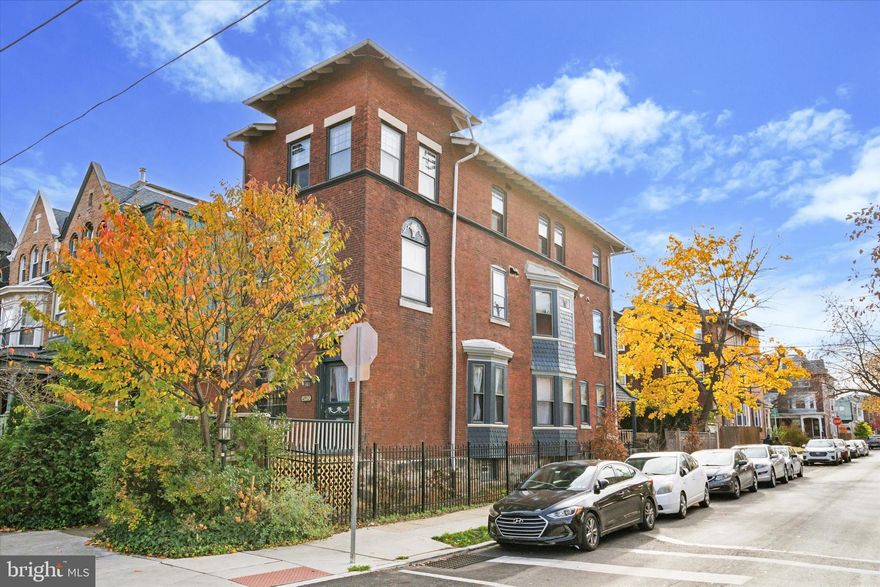 This majestic three-unit corner property with a coveted garage is a great candidate for an owner occupant looking for a long-term investment and home in one, a house hack for friends seeking a cooperative lifestyle while preserving privacy with separate living quarters, or as a straightforward turnkey addition to an investor’s portfolio–and the potential for a future condo project comes to mind for any of the above. All three apartments are spacious and brimming with classic West Philly charm; units 2 and 3 were totally renovated for two of the owners to occupy, while the first-floor unit received a nice facelift, making it uber-rentable. Unit 1 has private front porch access, a vestibule entrance and large coat closet, newly refinished original pine floors throughout; living room with oversized arched window; a bay window with bench in the renovated kitchen; bathroom with mid-mod black and yellow tile; in-unit laundry; and two good-sized bedrooms–one with a bay window and the other with access to the rear porch and yard. The second and third floors have both been renovated with stylish, high-quality finishes, and both feel like stepping into a lifestyle mag, albeit in notably different ways. Unit 2, which has new Bruce oak floors that run throughout, has a more modern sensibility, with Scandinavian-inspired finishes that blend nicely with the original details. The open-plan living space with two exposures has a decorative fireplace with original mirrored mantel, a sweet set of leaded glass windows along with a large closet, and a sleek kitchen with breakfast bar and stainless steel appliances including a GE French door fridge and a Frigidaire five-burner range with architectural hood. Green Muuto pendant lights and cabinet hardware are set against white quartz countertops and ample white Shaker-style cabinets; there’s also an enormous pantry closet. The center room has another sweet leaded glass window, an extra-large closet and a full wall of built-in shelving. It is currently used as a den; all it needs for total privacy is a set of barn or double doors. The large rear bedroom is flooded with light from two exposures. A hallway laundry closet with GE frontloaders and a mid-mod pink and black bathroom with original cast iron tub complete this space. Unit 3, with a more traditional feel, also offers a large open-plan living space with two exposures and a gorgeous U-shaped kitchen. Here original pine floors run throughout and the living room features a charming beadboard built-in bookcase and coat closet. This kitchen has classic globe pendant lighting, Frigidaire stainless steel appliances featuring a five-burner range and French door fridge, warm butcher block countertops and white polished ceramic subway tile backsplash. The good-sized middle bedroom with double windows has a large closet, and the rear has more than enough space for a king-size bed, a large closet and two exposures. Off the hallway is access to the standing-height attic, a large utility closet with GE frontloading laundry and a mid-mod green tile bathroom with pedestal sink and original cast iron tub. The basement with utilities and additional storage is accessed directly from the charming rear yard, which is enclosed at the rear by the detached one-car garage. This lovely building with two mature cherry trees (one edible!) on a lovely block of Hazel Ave is in an ideal Cedar Park location that’s just a hop, skip and a jump to Baltimore Ave.