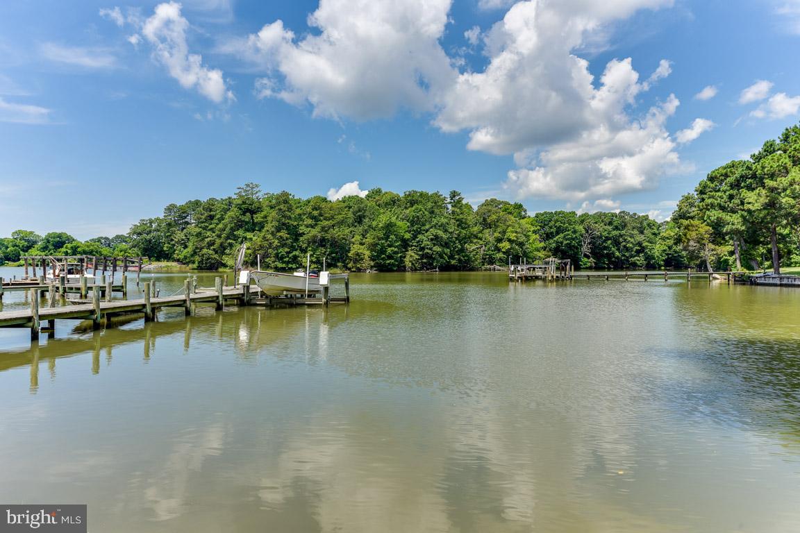 Summer fun never needs to end with this beautiful waterfront retreat. Enjoy the private pier and boat lift (approx. 14000lb) to accommodate all your water activities whether crabbing, fishing or boating. Rest easy knowing there is approximately 150' of riprap installed to secure the shoreline. The main level of the home includes the primary bedroom and bath with separate tub and shower as well as double vanity. This primary bedroom also has a private deck to enjoy your morning coffee and watch all of nature come to life. The kitchen is beautiful with upgraded cabinetry, corian counters and mostly brand new stainless steel appliances. Both the dining area and living room face the water with wonderful views of the sunset. Hand-scraped wood floors throughout the main with carpet in the bedrooms. For convenience, the laundry room is located off the primary bedroom with plenty of additional shelving. A beautiful deck for inside outside entertaining and cooking out is just steps from your living space. The upstairs includes the fourth bedroom, large additional living space and cozy nook for reading and hanging out. The lower level of the home is unbeatable! Shiplap walls, sliding barn doors and the third full bath. This is the perfect spot for entertaining, eating crabs, working out, you name it. Don't forget to check out the screened porch which is a walk out from the lower level. Additional storage finishes off this wonderful lower level with multiple garage spaces and a separate workshop. This home has been freshly painted in anticipation of its new owners. What a beauty! I know you'll agree that this home was well worth the wait! ****Professional pictures to post on Wednesday. In the meantime, check out the prior video at top of the page (keeping in mind that we have new neutral light paint and new appliances)