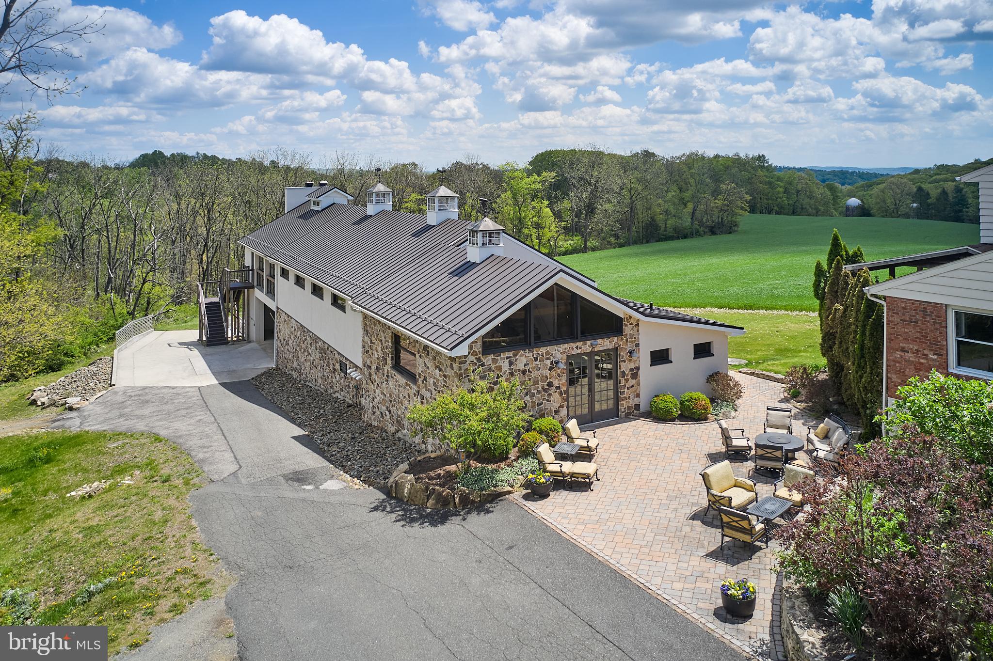 Attention Entrepreneurs and Visionaries! Are you ready to own a versatile state-of-the-art, environmentally sustainable venue in southern Berks County just off of busy Route 100? Look no further than this remarkable opportunity to own this inviting 7,500 sq ft venue custom-designed for entertainment and/or production. With easy access from the 422 corridor and the Lehigh Valley, this Bechtelsville masterpiece with cutting edge features boasts incredible Pennsylvania farm views! The venue comes complete with a temperature controlled and humidified garage and a 3-bedroom residence for offices and manager’s housing and/or complimentary bed & breakfast.
Nestled amidst 3+ acres of pristine grounds, this Venue sets the stage for potential, unforgettable events. From weddings and corporate retreats to intimate family reunions, this flexible event spaces can be tailored to any occasion. Looking for a perfect site for a turnkey brewery, distillery, or winery? This is it! This venue has a world of possibilities.
Conveniently located less than 10 miles from Bear Creek Mountain Resort, 40 miles from Philadelphia and just 90 miles from New York City, the Venue is not only stunning, but also sets the standard for eco-friendly innovation. 48 south facing solar panels provide the electricity and 7 geothermal wells provide efficient heating and cooling. The building's warm wood and stainless accents create a welcoming ambiance, while accessible restrooms and a high-tech catering equipment kitchen supply maximum functionality. A sun filled mezzanine entertainment space is open to the lower level production floor allowing for captivating views of the action below. The generously sized covered deck features a cozy, stone wood-burning fireplace plus built-in space heaters, various seating configurations, and glass garage doors that open to the picturesque surroundings seamlessly blending indoor and outdoor experiences for your guests. Practical considerations include a French drain system for easy wash down cleaning, an air flushing system for optimal air quality, a custom water treatment and delivery system, access to glycol and argon, a production area office, and a huge and tall underground dry storage for supplies and inventory.
But wait, there's more! What sets this venue apart is its potential for additional revenue streams. The property also includes a residence that can be utilized as a bed and breakfast or staff housing, offering the perfect blend of convenience and comfort for you and your team. Savvy buyers have the opportunity to maximize the property's earning potential. A charming 3 bedroom, 1.5 bath guest home sits adjacent to the venue. With its own living room, dining room, kitchen and family room area, this home is perfect for guests, staff offices and sales distribution. Whether you choose to offer accommodations for overnight guests or create a welcoming home for on-site management, the venue offers the perfect blend of business and pleasure.
If you are an entrepreneur looking to launch your next venture or an investor seeking a rare opportunity, this Venue provides the perfect blend of luxury and functionality and is the ultimate package. With its prime location, versatile amenities, and endless potential, it's time to elevate your vision and make your mark!