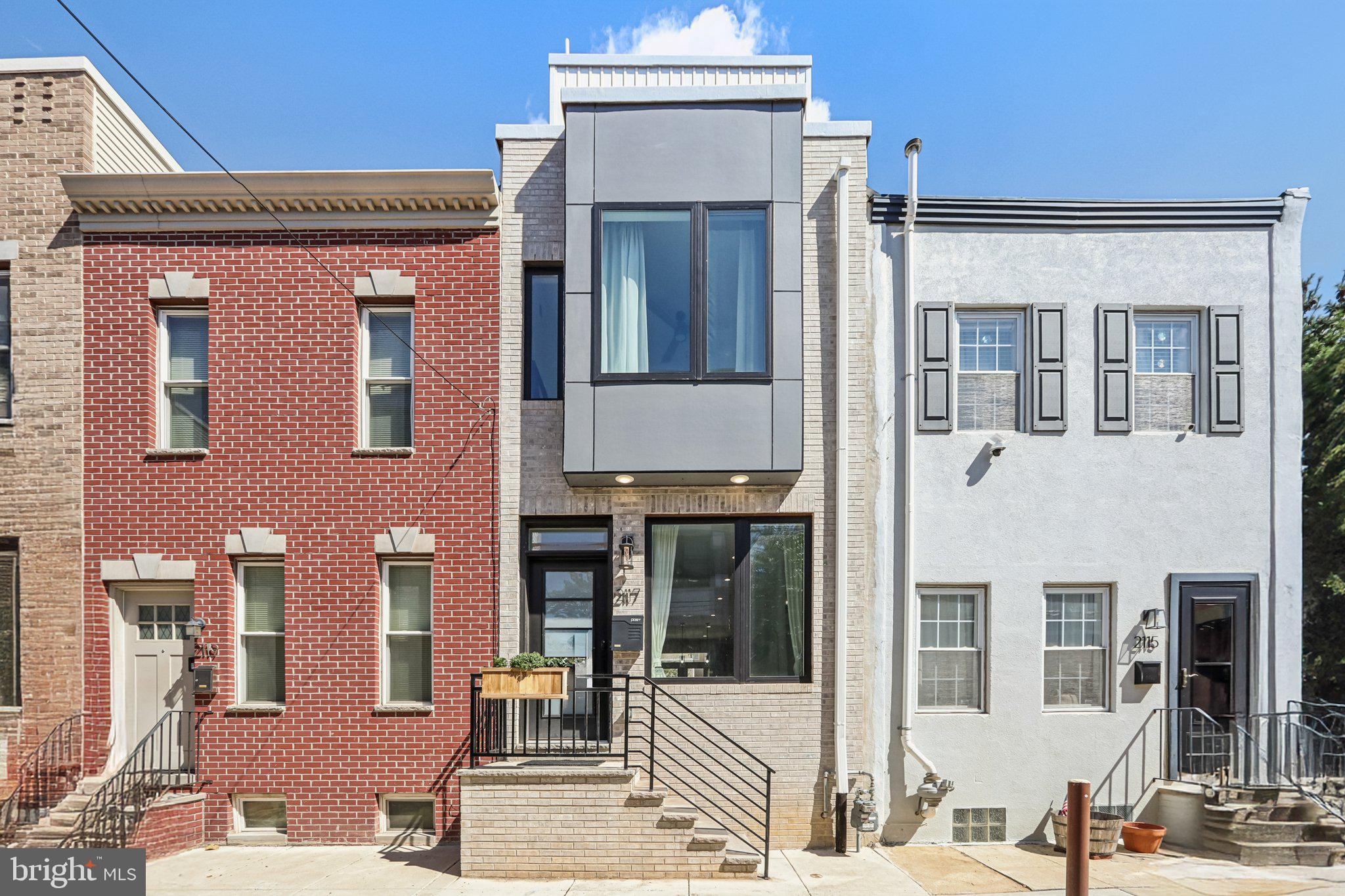Welcome to this stunning, less-than-3-year-young rowhome located in the heart of Point Breeze, offering approximately 7 years remaining on the tax abatement. This beautifully designed home combines modern luxury with thoughtful functionality, starting with an open-concept main level filled with warm tones, abundant natural light, and high-end finishes throughout. The spacious living room flows seamlessly into the dining area and into a gourmet eat-in kitchen, featuring Quartz countertops, a breakfast bar with seating, stainless steel appliances, a pantry, pot filler over a 5-burner gas range, and an exterior-vented hood. Glass doors off the kitchen open to a private rear patio, perfect for outdoor entertaining or relaxing. Upstairs, you'll find two generously sized bedrooms that share a full hall bathroom equipped with a tub/shower combo and a smart mirror, along with a conveniently located laundry area. The third floor is entirely dedicated to the primary suite, complete with a walk-in closet outfitted with custom California Closets built-ins and a spa-like ensuite bathroom. This luxurious space includes heated tile floors, a dual vanity, smart mirror, and a glass-enclosed walk-in shower with a rainfall head and a large window that fills the room with natural light. A wet bar on the landing leads to the private rooftop deck, which boasts unobstructed views of the city skyline—an ideal space for entertaining or relaxing. The fully finished basement offers additional versatile living space to suit your needs, along with a half bathroom and custom built-in shelving under the stairs for organized storage. Additional upgrades include a built-in speaker system wired throughout the entire home and rooftop deck, a front video doorbell, Nest keyless entry, and security system capabilities (with all equipment installed and ready for activation). This move-in-ready home is the perfect blend of style, comfort, and convenience—schedule your private showing today! Mortgage savings may be available for buyers of this listing.