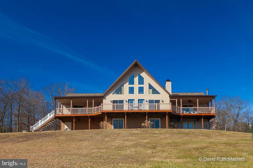 BEST & FINAL OFFERS DUE BY FEB. 15TH AT 5PM. Welcome to your very own private 35+ acre wooded retreat, nestled among a serene rolling landscape and enveloped by the tranquil ambiance of nature. This picturesque sanctuary offers unparalleled peace and quiet, accompanied by breathtaking panoramic mountain views that stretch as far as the eye can see. With unrestricted access to the beauty of the great outdoors, this home beckons those seeking solace and connection with the environment. The Cacapon River is just beneath the ridge on the other side of the pond. The spacious and inviting chalet has been wonderfully curated featuring a massive great room adorned with a soaring cathedral ceiling with exposed wood beams and ceiling fans. Floor-to-ceiling windows grace this room, framing the majestic vistas that unfold beyond. The open floor plan seamlessly integrates the great room with a gourmet kitchen boasting granite countertops, a tiled backsplash, center island, stainless steel appliances, and beautiful engineered hardwood flooring. Just off of the kitchen is a laundry room with access to a half bath and rear yard. The primary suite includes a large soaking tub, separate shower, double sink, separate vanity area, and spacious walk-in closet. The split floor plan ensures privacy and convenience, while the potential for a second primary suite, complete with its attached jack and jill bathroom, offers flexibility and a quiet retreat for your guests to relax. The mostly finished walk-out basement provides endless possibilities for customization and ample storage space. It could even be converted into an apartment or in-law suite. A new furnace installed in 2023 and updated kitchen appliances, newer roof, newer heat pump, and new carpeting all ensure modern comfort and efficiency. Warmth abounds with efficient wood stove heating in addition to a cozy wood-burning fireplace. For peace of mind during inclement weather, a whole house generator stands ready to provide backup power. Every room of this home seamlessly integrates with the outdoors, inviting you to savor the tranquility and natural beauty that surrounds you. Whether you're sipping your coffee from the spacious front deck or sitting pond-side watching the goldfish gracefully darting beneath the water's surface, this unrestricted property offers endless opportunities to unwind and reconnect with nature. Raise your own animals, garden, homestead, and even hunt on your own property – the possibilities are endless! Must have an appointment to tour the property. Please arrive prepared to remove your shoes as this home is immaculate! Prepare to be amazed and to see why we call this the BEST Virginia!