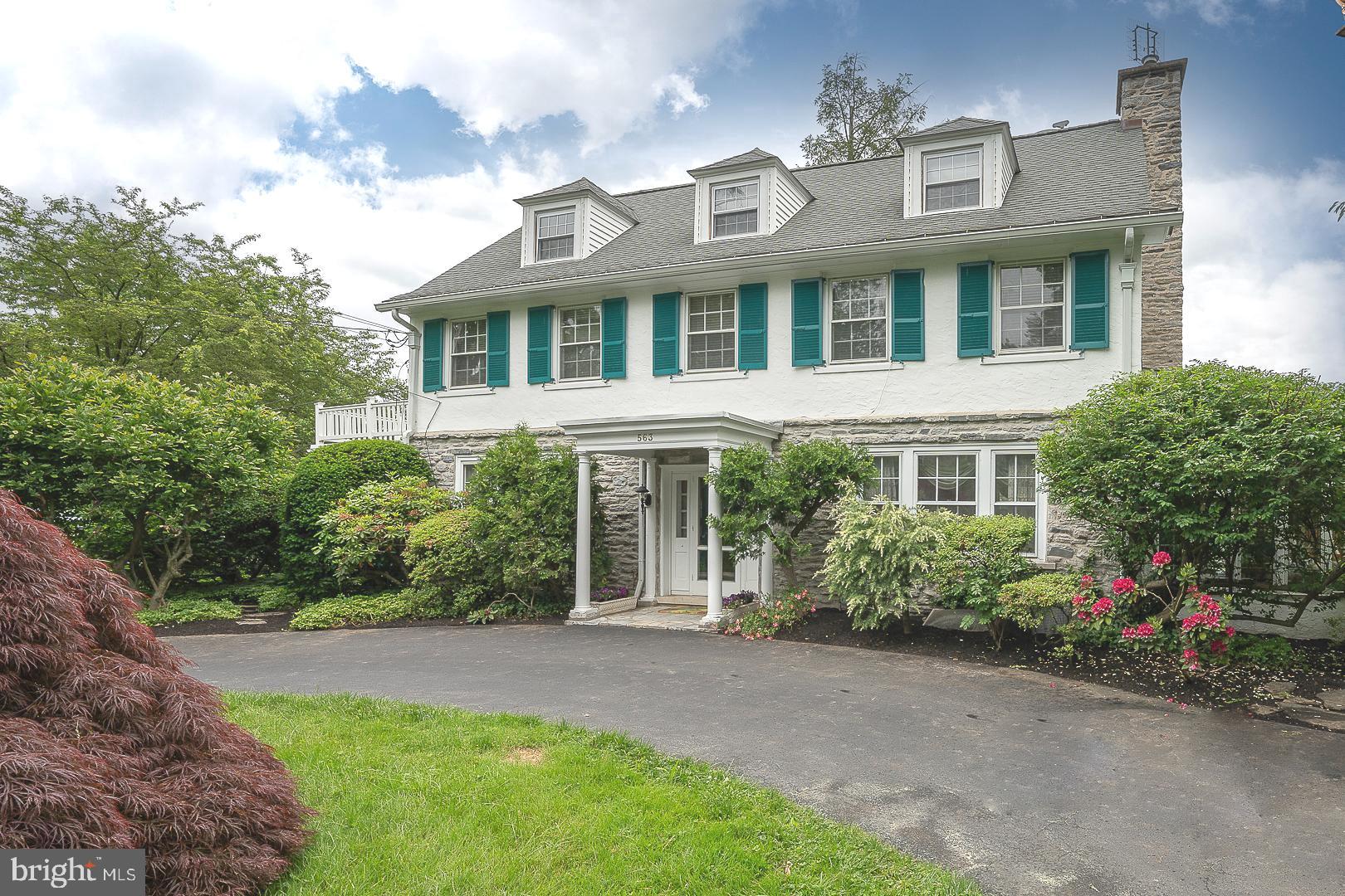 Welcome to an exceptional classic Main Line Colonial residence nestled on one of Merion Station's most sought-after streets. Beautiful corner lot with an expansive circular driveway offering ample parking for up to six cars plus an additional driveway to a two-car heated garage. Mature landscaping surrounds this home providing privacy and offering both rose and vegetable/herb gardens. The covered front door portico welcomes you to the gracious foyer with exquisite woodwork detail, beautiful hardwood floors, and the warmth of old-world charm. The expansive sized Living Room is complete with wood wood-burning fireplace, built-ins, and a large picture window. Glass double French doors on either side of the fireplace lead to a stone-floored sunroom. Surrounded by windows and abundant sunlight, this warm and inviting room faces gardens on all sides. It is the perfect tranquil place to relax and unwind and is heated for added comfort. The generously sized Dining Room has beautiful hardwood floors and an entrance to an open covered side porch for easy outside entertaining. The gourmet eat-in Kitchen with dark wood cabinetry has granite countertops and an island for additional workspace. Appliances are all stainless steel, Sub Zero refrigerator/freezer, Thermidor gas range with electric oven, built-in microwave, stainless sink with water filter, and dishwasher. There is a fabulous glass-doored built-in cupboard, room for a kitchen table, and a built-in desk with shelving. Behind the kitchen, you will find the main floor laundry room. An outside exit to the side driveway and heated two-car garage allow easy access with packages and groceries into the kitchen area. The back hallway from the kitchen to the main foyer has a built-in cabinet, entrance to the basement, powder room and leaded glass door coat closet. An additional outside entrance to the rear gardens, garage, and basketball court completes this lever. There is ample outdoor space for recreation and relaxation! The large full basement has been freshly painted with a French drainage system and plenty of shelving for storage. An open staircase leads to the second floor with hardwood flooring. At the top of the stairs, there is a small bedroom, perfect for an office or nursery, plus two generously sized bedrooms with a jack & jill hall bath with a soaking tub. One bedroom has a door to the second-floor balcony. The prime bedroom suite consists of a dressing room/closet, an updated full bath with double vanities and marble counters, and an oversized bedroom with plenty of natural light. The third floor opens to a large carpeted Family Room/Bedroom with a walk-in storage closet. An additional two bedrooms and a full bath complete this floor. Attention to detail and maintenance show clearly throughout this residence. Three-zone AC, upgraded plumbing and updated electrical, etc. Enjoy the convenience of shopping, restaurants, houses of worship, effortless commutes via Merion train station, and easy access to major highways and public transportation as well as award-winning Lower Meiron Schools.