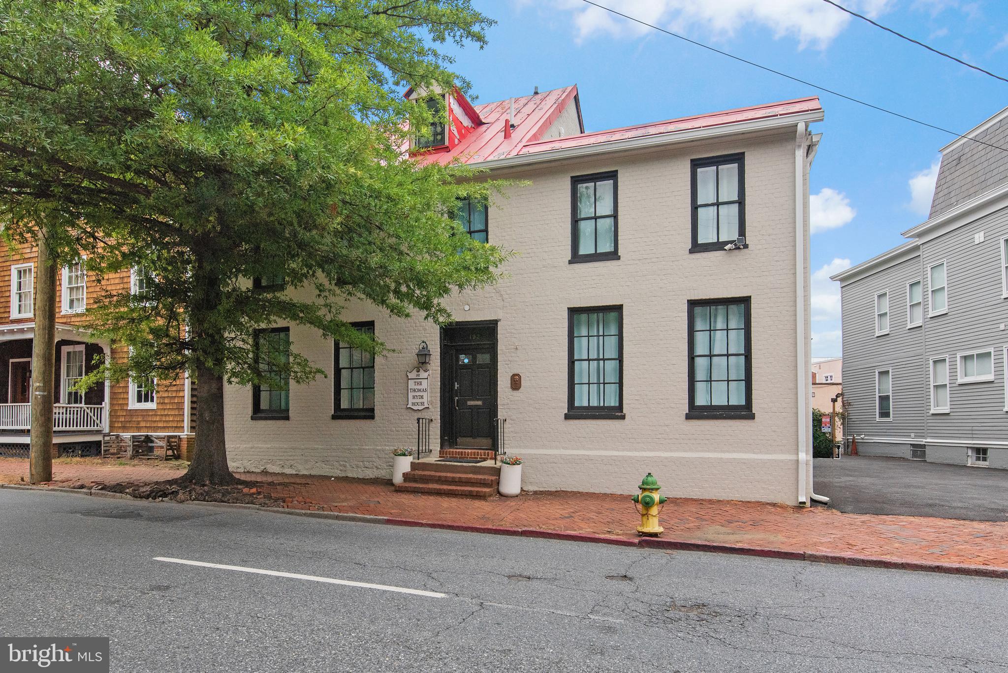 Welcome to the Thomas Hyde House – a rare opportunity to own a piece of Annapolis history in the heart of downtown. Built in 1769, this impeccably restored Federal- style property blends 18th-century charm with modern luxury. Perfectly situated on sought- after Duke of Gloucester Street, this vibrant and colorful home offers stunning views of the Maryland State House and extremely rare off-street parking for nine vehicles.
Originally configured as office space, the residence has been reimagined into six spacious bedrooms and four full baths across two beautifully remodeled levels, with the potential for third floor updating plus a large basement with ample storage and updating space. The first floor offers true single level living with a primary suite and second bedroom, while the second level features four additional bedrooms and a convenient laundry area.
No detail has been overlooked – from new appliances, countertops, and cabinetry to frameless glass showers, ceramics, extensive trim and molding, recessed lighting, fresh interior and exterior paint, updated flooring throughout and more. The result is a turnkey home where historic character meets modern sophistication & luxury.
The property is offered with negotiable furnishings, electronics and art, The Thomas Hyde House is as versatile as it is fun and captivating. Just steps from downtown Annapolis shopping, dining, yacht clubs, local marinas & major commuter routes. Whether as a primary residence, investment property, or distinctive downtown retreat, this is an Annapolis treasure ready for its next chapter.