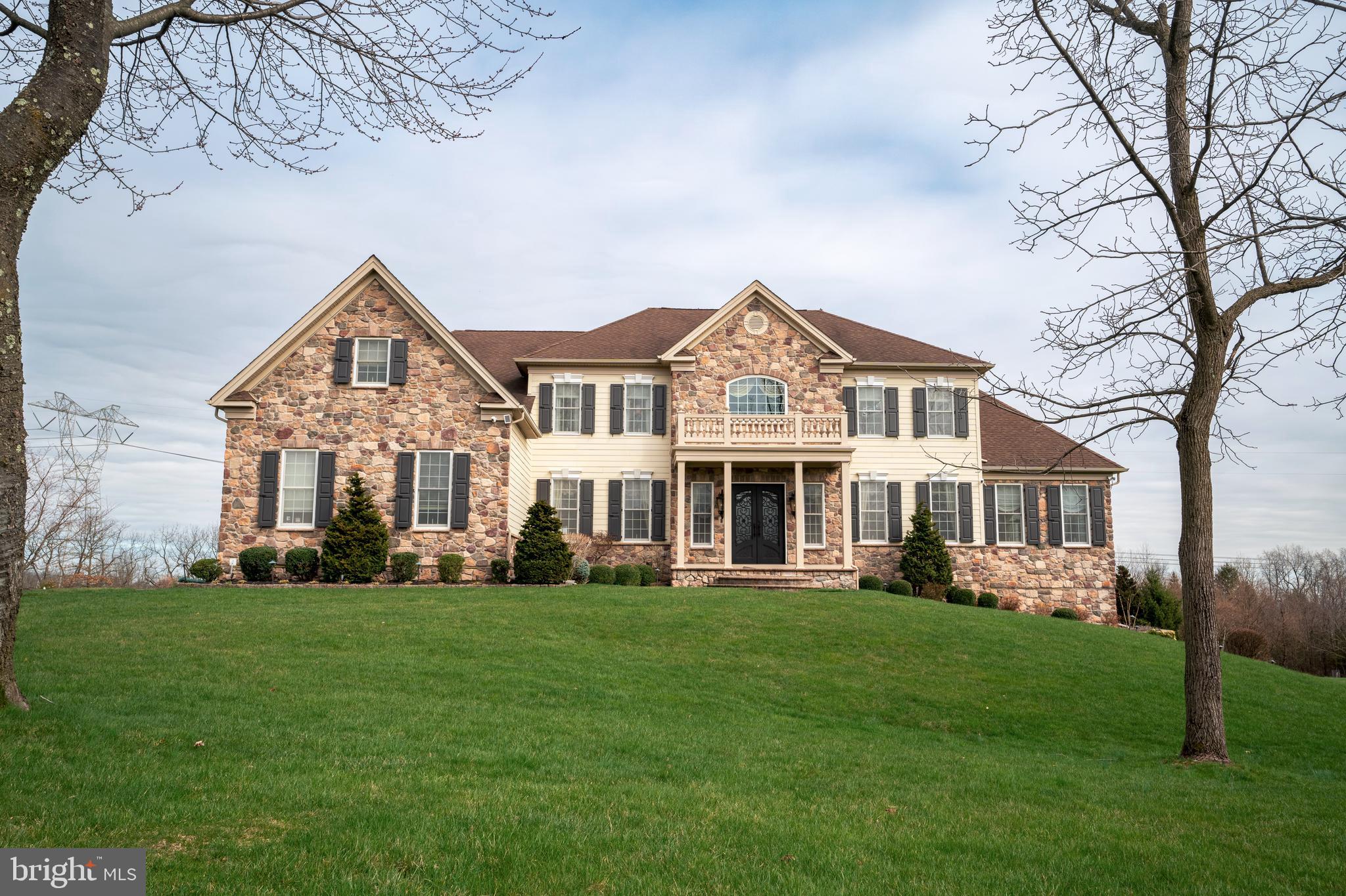 Indulge in the epitome of opulence within this sprawling 6,000 sq. ft. residence in the esteemed Estates at Hilltown. Majestically situated against preserved land, this four-bedroom haven boasts five full bathrooms, two half baths and 3 car garage, greeting you with a captivating butterfly staircase in the foyer. The main level unfolds with a formal living and dining room adorned in hardwood floors and custom crown molding. A vaulted-ceiling conservatory beckons, featuring a wet bar with granite countertops and a seamless transition to a vast composite deck overlooking the expansive backyard. The chef's kitchen is a culinary masterpiece with double wall ovens, a pantry, and granite countertops framing awe-inspiring views. Experience sheer magnificence in the great room- a masterpiece of design. Towering two-story ceilings, rich hardwood floors, coffered ceiling, a gas fireplace with floor to ceiling stone, and a second staircase redefine luxury living. An office, 2 powder rooms, and mudroom complete this floor. Ascend to the second level, where the primary suite awaits with vaulted ceilings, a sitting room, and a lavish en suite featuring heated floors, Jacuzzi tubs, and an oversized walk-in shower. Two bedrooms boast Juliet balconies with attached bathrooms, and a fourth bedroom offers its own en suite. Technological marvels abound, from the ozinator pool and new Bose system to the updated lifestyle system and outdoor speakers with lifetime warranty. The entire house is fortified with Ring flood and spot cameras, ensuring security. The residence, adorned with Timberlane shutters, presents a full irrigation system and a basement ripe for customization. This home is a sanctuary for those seeking a luxurious retreat with unparalleled amenities.