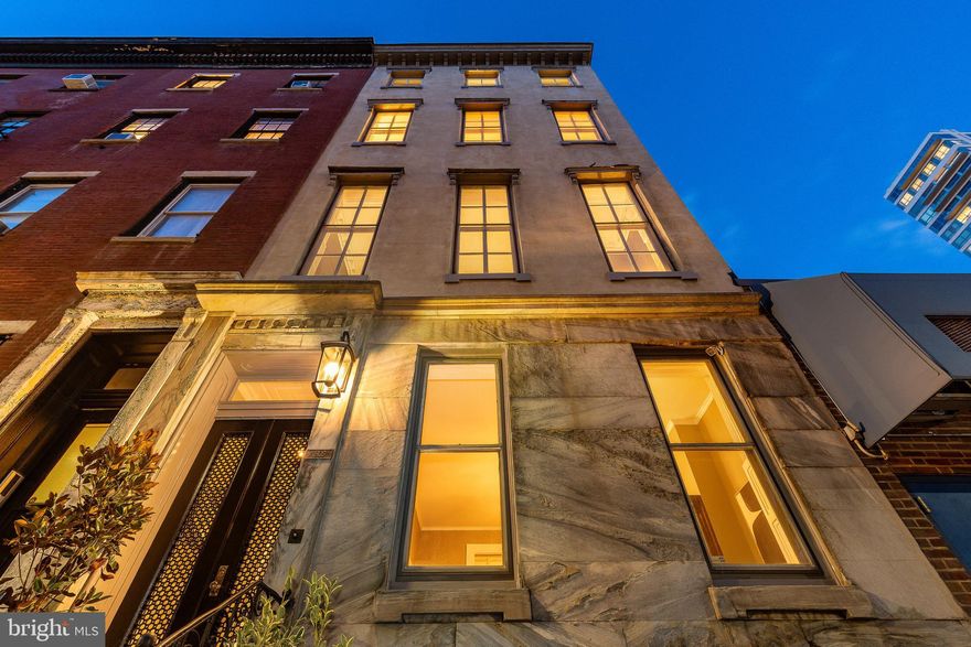 Commanding and architecturally distinguished, this 1867 Italianate marble-front townhouse sits just one-half block from Rittenhouse Square. Offering approximately 3,300 square feet across four full stories, this 20-foot-wide residence includes four bedrooms, two full baths, a main-level powder room, a private courtyard, and one year of prepaid off-street parking on the 1800 block of Manning Street with acceptable offer. A classic Philadelphia marble stoop, bracketed cornice, and tall parlor-level windows immediately establish the home’s historic pedigree.

Throughout the home, original coffered plaster ceilings with soaring heights, abundant natural light, pocket doors, curved architectural elements, stained and leaded glass windows, and three wood-burning fireplaces reflect exceptional 19th-century craftsmanship.

The first floor offers a refined arrival, beginning with an elegant Italianate vestibule entry featuring double doors with pierced metal panels, glass backing, and an etched-glass transom, framed by preserved period millwork. A gallery-style entry hall with ceilings nearing 11 feet, original coffered plaster detailing, graceful archways, and inlaid hardwood floors leads to a gracious parlor with a wood-burning fireplace and tall windows.

The kitchen was reimagined in 2019 into an elevated and highly functional space with custom cabinetry scaled to ceiling height, integrated backlighting for a soft ambient glow, timeless stone surfaces, and a quartz-topped island with seating for four. High-end appliances include a gas range with custom hood, refrigerator, and dishwasher. A discreet powder room and direct access to the private courtyard on this level complete the main floor.

The second floor is the architectural showpiece, featuring approximately 18-foot ceilings, preserved plasterwork, ceiling medallions, and period moldings. The formal dining room is anchored by a statement chandelier and built-in display cabinetry. Original pocket doors open to the formal living room with tall south-facing windows, a commanding wood-burning fireplace, and rich architectural detailing—ideal for formal entertaining and daily living.

The third floor is dedicated to the primary suite, bathed in southern light and anchored by a wood-burning fireplace. A flexible dressing room or office area, multiple closets including a cedar-lined closet, and an en-suite bath with double vanity, glass-enclosed shower, and abundant natural light complete this level.

The fourth floor offers exceptional flexibility with three well-proportioned rooms (currently bedrooms, one used as an office), a full bath, a kitchenette, and a dedicated laundry area—ideal for guests, extended stays, or work-from-home separation.

An unfinished basement with a separate street entrance provides excellent storage. Additional features include a gracefully curved staircase, architecturally significant curved wall, updated period-appropriate lighting, a comprehensive security system, and major infrastructure upgrades including updated electrical, plumbing, gas lines, zoned HVAC, and a tankless hot water system.

Located in close proximity to Rittenhouse Square’s dining, shopping, parks, and cultural institutions, 1805 Spruce Street offers an ideal blend of historic architecture, modern infrastructure, and premier city living.