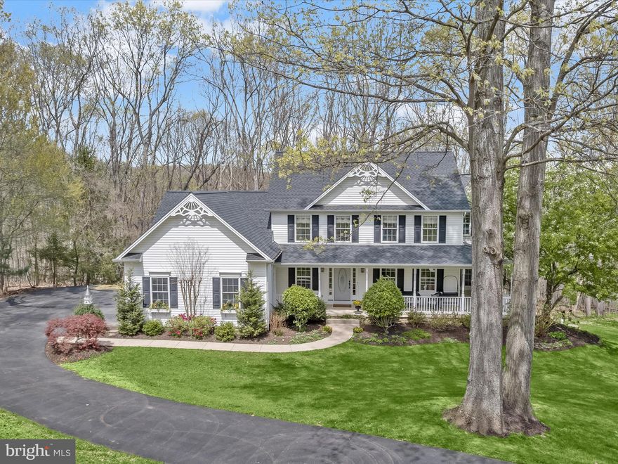 Tucked away on a quiet cul-de-sac and surrounded by mature woods, this exceptional five-bedroom, two-and-a-half-bathroom home offers a refined lifestyle on over three peaceful acres. A wraparound front porch welcomes you with charm and serenity, setting the stage for the thoughtful design and timeless elegance found throughout. Sunlight fills the main level, where detailed crown molding, classic wainscoting, and gleaming hardwood floors create a warm and inviting atmosphere. The foyer opens to a spacious front living room and an elegant formal dining room featuring a bay window that bathes the space in natural light. A glass door connects to the kitchen, highlighting brand new stainless steel appliances, a pantry, and a cozy breakfast nook for casual meals. At the heart of the home, the family room impresses with a soaring cathedral ceiling, a floor-to-ceiling stacked stone gas fireplace, and three walls of windows framing tranquil woodland views. Step out onto the side deck for a morning coffee or unwind on the second deck off the breakfast nook—perfect for grilling, lounging, or dining outdoors. Also on the main level are a stylish powder room, a dedicated laundry room, and access to the oversized three-car garage. Upstairs, the primary suite feels like a retreat, complete with a cathedral ceiling, dual walk-in closets, and a luxurious bathroom with a soaking tub, walk-in shower, and double vanity. Down the hall are three additional bedrooms and a well-appointed full bathroom with a tub shower and dual vanity. Finishing the upper level is the fifth bedroom, paired with an attached bonus room—ideal for a home office, playroom, or creative space. Downstairs, the walk-out lower level offers endless possibilities for future living space, already equipped with a bathroom rough-in. Other highlights include a new roof (2025), new carpet in bedrooms (2025), a high-efficiency water heater (2022), and pre-wiring for a generator. Located just minutes from the NCR Trail, Gunpowder Falls State Park, and I-83, this home offers the perfect balance of privacy, elegance, and convenience.