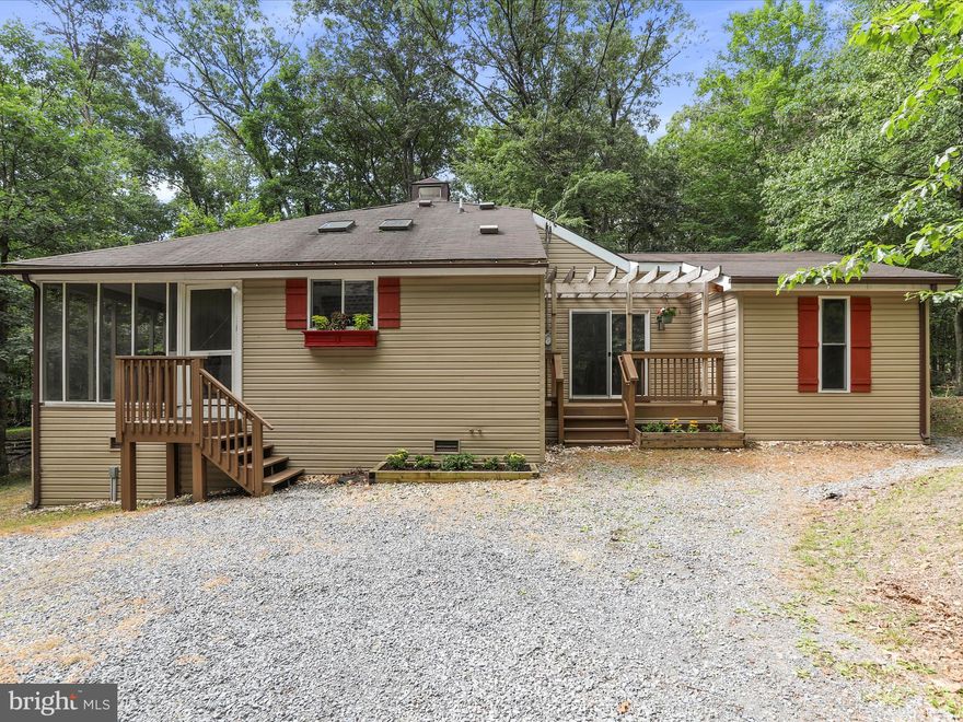 Woodland Wonder with Versatile Garage Studio
61 Shawnee Trail | The Woods, WV
Perched on a serene 1.06-acre wooded lot that backs to the protected Sleepy Creek Wildlife Management Area, this beautifully maintained modified Dogwood model is more than a home — it’s a lifestyle retreat. With 4 bedrooms (including loft), 2.5 baths, and an expansive detached garage with finished upper level, this is a rare opportunity to spread out, stay inspired, and live with purpose.

A welcoming screened-in porch sets the tone, leading into a bright kitchen that flows effortlessly into the dining area, great room, and flexible living space. Vaulted ceilings and abundant natural light give the interior a spacious, airy feel, while a pellet stove adds warmth and ambiance. The main level includes a primary suite, two guest bedrooms, and a full guest bath. Upstairs, the loft includes its own half bath and is ready for guests, creative use, or quiet retreat.

Now, let’s talk garage.
This new detached structure is a game-changer. With 960 square feet total—480 square feet on each level—it offers serious flexibility. The lower level provides traditional garage parking with space for a workshop or home gym. Upstairs, the finished upper level is a blank canvas—perfect for a home office, art or yoga studio, music room, or hobby headquarters. The entire building is powered by its own 60 AMP subpanel, giving you the capacity for tools, lighting, fitness equipment, or creative tech setups with room to grow.

Outdoors, enjoy the screened porch and rear deck surrounded by woods, with trails and wildlife just beyond your doorstep. Select furniture has the option to convey, including a one-of-a-kind dining table and counter stools—adding a touch of personality to your next chapter

Standout Features:
– Detached 2-level garage with 960 sq ft and a dedicated 60 AMP subpanel
– Vaulted ceilings & pellet stove in great room
– Spacious screened porch + sunny rear deck
– Flexible loft with half bath
– 1.06-acre lot backing to Sleepy Creek Wildlife Management Area
– Washer/dryer included
– Located in The Woods with optional access to amenities

Membership Options:
This home does not include a Woods Club membership, but buyers may add one.

Class A membership (includes golf and full amenities) requires a $3,150 one-time initiation fee plus $2,600/year in dues, made whole by paying dues retroactive to March 1, 2024.

Class B membership (excludes golf) requires the same $3,150 initiation fee, with $1,600/year in dues, also retroactive to March 1, 2024.

With membership, you’ll unlock access to everything that makes life in The Woods so special—championship golf, indoor and outdoor pools, tennis and pickleball courts, a fitness center, dining, and a vibrant year-round social calendar.

A one-of-a-kind setting, a flexible floorplan, and a garage with big dreams—this is where your next chapter begins.