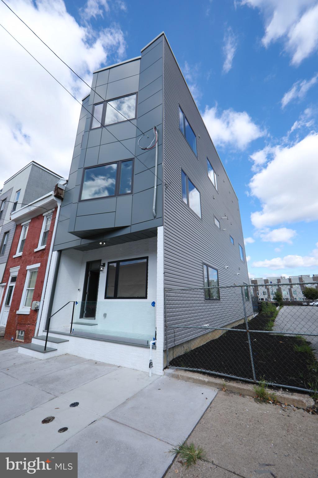 Step into sophisticated city living at this striking 3-story townhouse nestled in the vibrant Olde Kensington neighborhood—just steps from the energy of Frankford Avenue in Fishtown and the bustling Piazza in Northern Liberties. Spanning over 4,000 square feet, this architectural gem is a rare find, showcasing sleek modern finishes, gleaming marble accents, and meticulous design at every turn. From the moment you enter, you're welcomed by a loft-inspired first floor with soaring 10-foot ceilings, custom marble and granite surfaces, and abundant natural light streaming in from three exposures. The chef’s kitchen is a showstopper, featuring a dramatic waterfall island, perfect for both casual dining and elegant entertaining. Just beyond, a private courtyard offers a peaceful outdoor escape with a stunning mix of steel, brick, and concrete—ideal for al fresco gatherings. A secured private parking space is accessible through the rear gate, adding both convenience and peace of mind. The centerpiece of the home is a custom glass-walled staircase that flows seamlessly through all three levels, highlighting the home’s open, airy feel. On the second floor, you'll find two generously sized bedrooms, each with modern en-suite bathrooms and stylish finishes. The third floor is a true sanctuary—the expansive primary suite offers spa-like luxury with a freestanding soaking tub, a spacious glass-enclosed marble shower, and a beautifully appointed bathroom that invites relaxation. The suite also includes a large, custom-fitted closet space and thoughtfully designed built-ins for storage and organization. Additional highlights include a fully finished basement with 9-foot ceilings and a wide-open floor plan ideal for a media room, gym, or home office. Step up to the rooftop deck and take in panoramic views of the Center City skyline—a perfect backdrop for relaxing or entertaining under the stars. With 3 private bedroom suites, 5 total bathrooms, 3 outdoor spaces, and high-end design throughout, and the added benefit of a 6 year tax abatement remaining, this home delivers unparalleled luxury in one of Philadelphia’s most exciting neighborhoods.