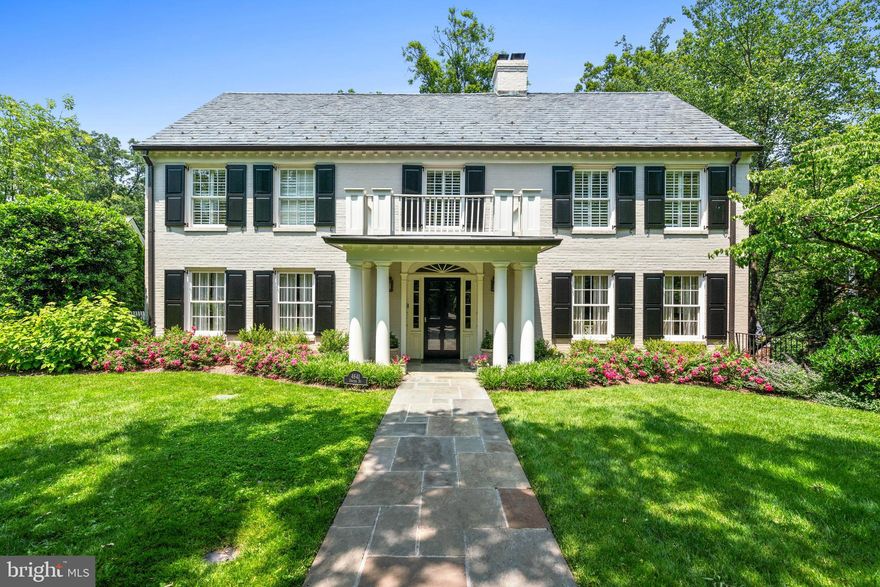 Ideally located in the highly desirable Wesley Heights neighborhood, this impressive residence is a notable example of Colonial Revival architecture. Set on a sprawling, nearly half-acre lot, it features a classic brick facade and an inviting front portico. Originally constructed in 1951, the home has been meticulously expanded and renovated by David Decker. The design and furnishings are by Andrew Law. The house offers a seamless blend of expansive entertaining spaces and cozy family living areas across nearly 10,000 square feet of interior space, making it ideal for both grand events and everyday comfort.
The elegance of the main level is introduced through a gracious entry foyer that features polished marble floors, ornate crown molding, and exquisite wall paneling, leading to a breathtaking two-story central reception area with a gas fireplace. The adjoining formal living room is bathed in soft natural light from south and east-facing windows, enhanced by lovely moldings and another inviting gas fireplace. A sophisticated dining room, large enough to accommodate lavish gatherings, seamlessly connects to a well-appointed butler’s pantry. The chef’s kitchen is a masterpiece of design, boasting a central island with a breakfast bar, custom cabinetry, and high-end appliances from Wolf and Subzero. The kitchen opens onto a charming breakfast room and a family room centered around a magnificent limestone mantel fireplace. The main floor also features a richly appointed library with wood-paneled walls, a fireplace and built-in bookshelves, a serene screened porch with park views, and a discreetly located powder room.
Ascending the stately staircase to the second level, one is greeted by a dramatic oversized window on the landing, offering picturesque views. The generously-scaled primary suite is a sanctuary of luxury, with a soaring ceiling, an arched window overlooking the verdant rear grounds, and dual walk-in closets. The en-suite bathroom is a spa-like retreat, complete with dual vanities, a glass-encased steam shower, a jacuzzi soaking tub, and a separate water closet. Four additional bedrooms each offer sunny, generously proportioned interiors and ample closet space, alongside a convenient laundry room.
The lower level is a haven for relaxation and entertainment, featuring an impressive recreation room with a stone fireplace and built-in media center, a convenient wet bar, and direct access to the rear terrace. This floor also includes an office adorned with extensive built-ins, a gym/game room, a media room equipped with a projector, a sixth bedroom with its own cozy fireplace and en-suite bathroom, and additional storage spaces. Additionally, there is a detached two-car garage.  
The outdoor area is a private retreat, surrounded by mature trees and meticulously landscaped grounds, with a large, flat backyard that adjoins Glover-Archbold Park, a 183-acre stream-valley park in Northwest Washington, DC on the western edge of Georgetown.  This home not only captures the essence of luxury and elegance, but also offers a warm and inviting atmosphere, making it a truly exquisite estate in the heart of Wesley Heights.