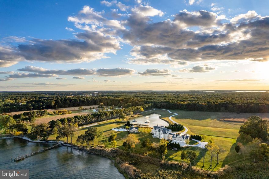 Arguably one of the most important new builds on the Eastern Shore, 7751 Rollyston Drive is a 91-acre estate on two parcels with 1500 feet of shoreline along a wide stretch of the beautiful Miles River. This turnkey property, just outside the town of St. Michaels, was completed in 2016. Prioritizing waterfront views, outdoor living spaces and comfortable living as well as for entertaining guests, the stately main house is accessed by a private, pea gravel road bordered by a pond with two gazebos and lighted fountains. The graceful circular driveway can accommodate multiple vehicles and leads to the rear entrance of the 4-car garage. The main residence with 12’ to 14’ ceilings offers 9 bedrooms with ensuite baths and 4 half baths. Accessible from the second floor of the main house as well as the garage, a stand-alone apartment showcases a great room with cathedral ceiling, pool table and game table with refreshment center, sound system, bedroom, and 1 ½ baths. Two outdoor porches are perfect for dining and entertaining and a porch off the second floor Primary Suite offers spectacular river views.

Built by a prominent DC builder for his own personal use, the structure of the house is truly commercial- grade and no detail was spared. All carpentry and flooring were custom designed and built with unparalleled craftsmanship, as evidenced by the moldings, staircases, and woodwork throughout the residence. Baths are Waterworks with marble tops and hardware is Baldwin Satin nickel. Media, HVAC, outdoor lighting, and security systems are controlled remotely through apps. 

Designed with an eye to entertaining there is a room for every occasion: a large eat-in Gourmet kitchen with granite countertops and Wolf/Sub-Zero appliances; a formal dining room that comfortably seats 14, two offices, a cozy family room with adjacent bar and living room, and a main level full bedroom with ensuite bath. Additionally, there is a Media room with 12 theater chairs, full bar, spa room and a large multi-purpose room in the lower level.

Outdoors, a flagstone path leads from the southern side porch to a heated salt-water  pool, pool house with two full baths, a covered outdoor kitchen and dining area with Wolf/Sub Zero appliances, and a 100” pier. The property houses a climate-controlled barn with plumbing, potential for 10 horse stalls and a second- floor hay loft or, the entire structure can become a car collector’s paradise. Next to the barn is a paddock and further down a service road is a cleared area for a future tennis/sport court. The caretaker’s house at the entry to the private drive has two levels, front and rear porches, three bedrooms, three and one-half baths and a two-car garage with two outdoor spaces.
 
When the current owners built the property, the expansive view of the Miles River became the focal point of the interior public rooms and now provides exquisite sunrise views. The partially rip-rapped shoreline has a small beach accessible by canoe, kayak, or shallow water boat. Co-Lister includes Cynthia Howar.